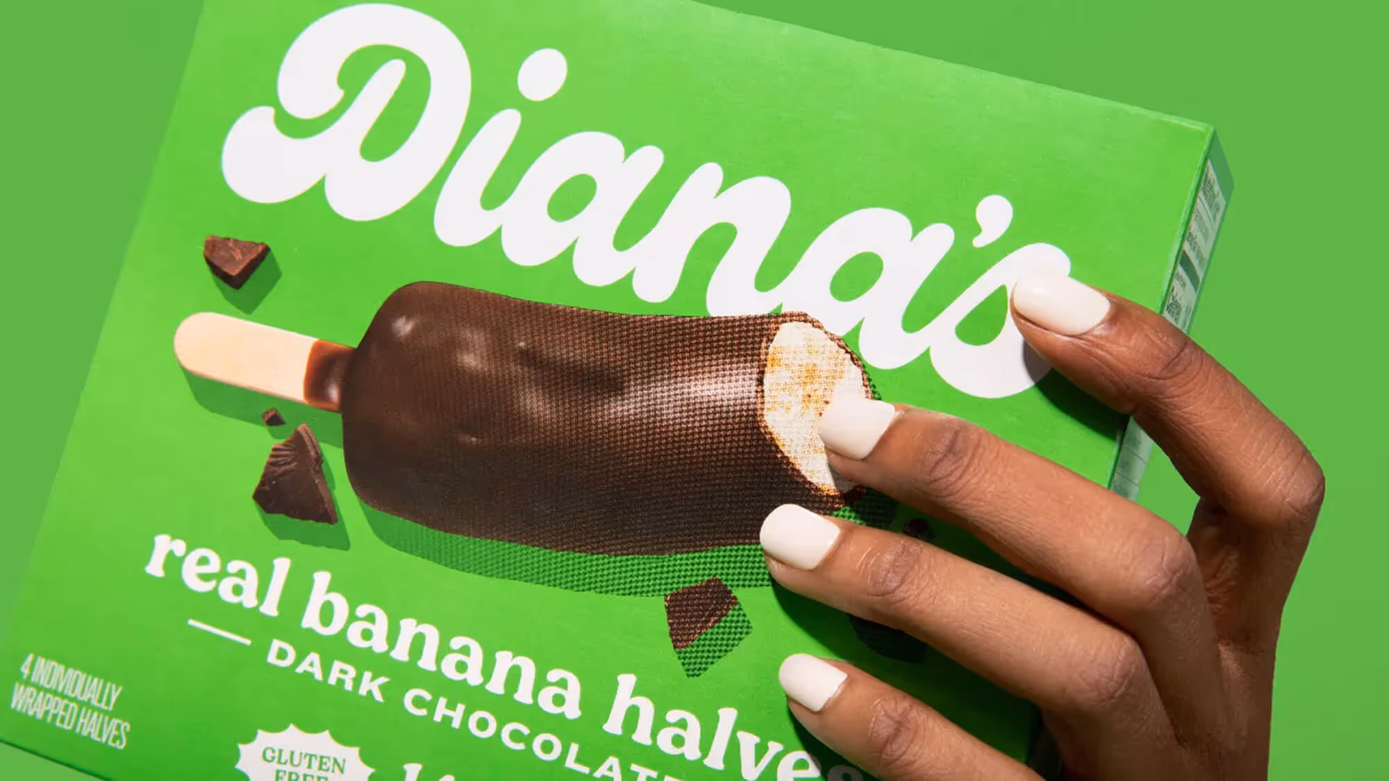 Hand with white nails tilting a green Diana's Dark Chocolate box toward camera.
