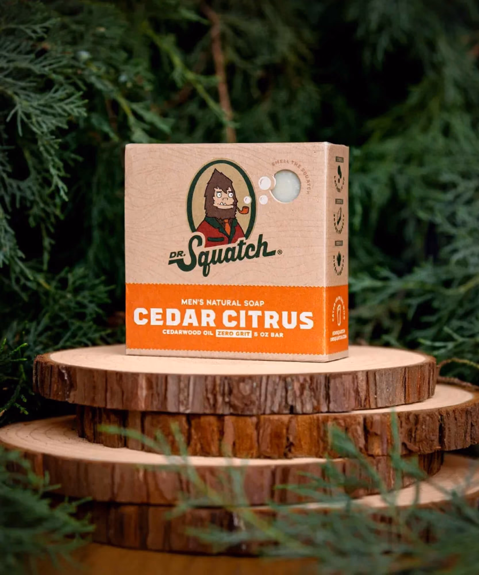 Cedar Citrus Dr. Squatch soap box on stacked wood slices with cedar branches and pine cones.