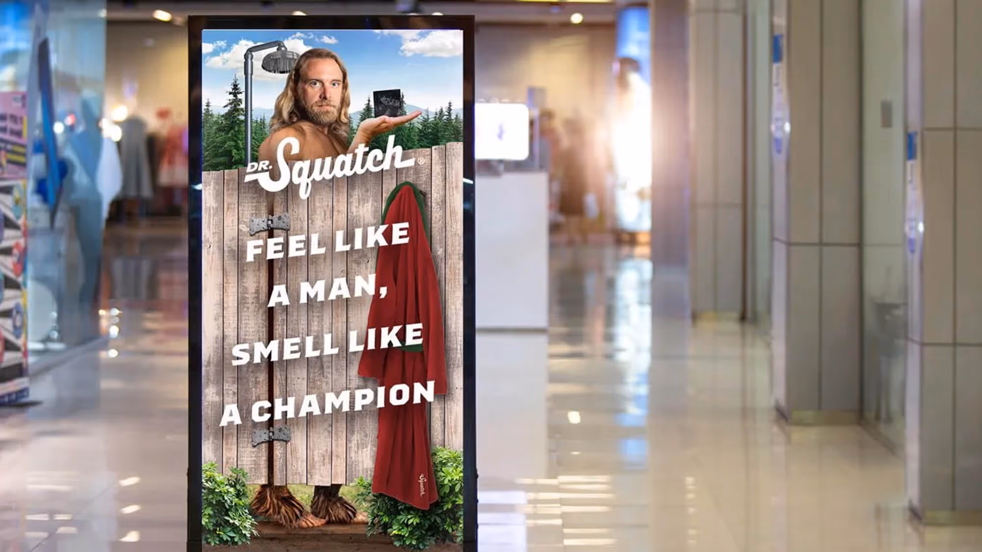 Mall digital sign with a Bigfoot character behind a shower fence; 'Feel like a man, smell like a champion'.
