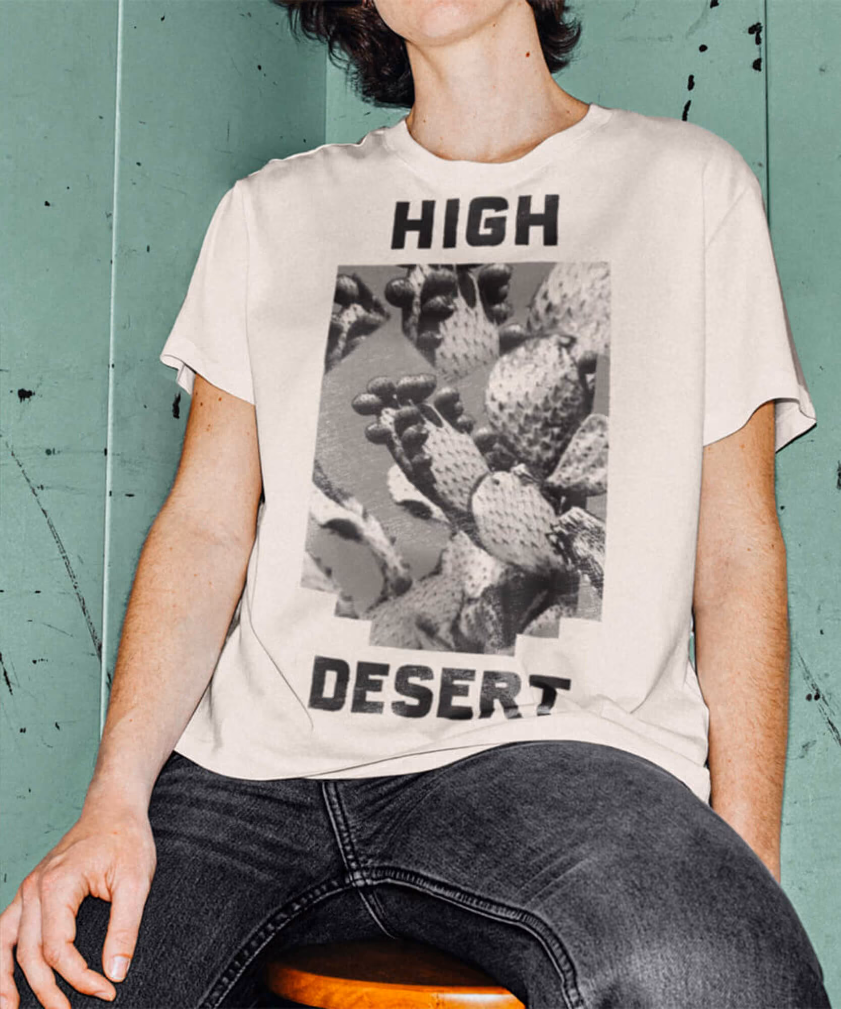 Hand holding an orange 'High Desert' cap by a flowering prickly-pear cactus; cream tee with cactus photo print.