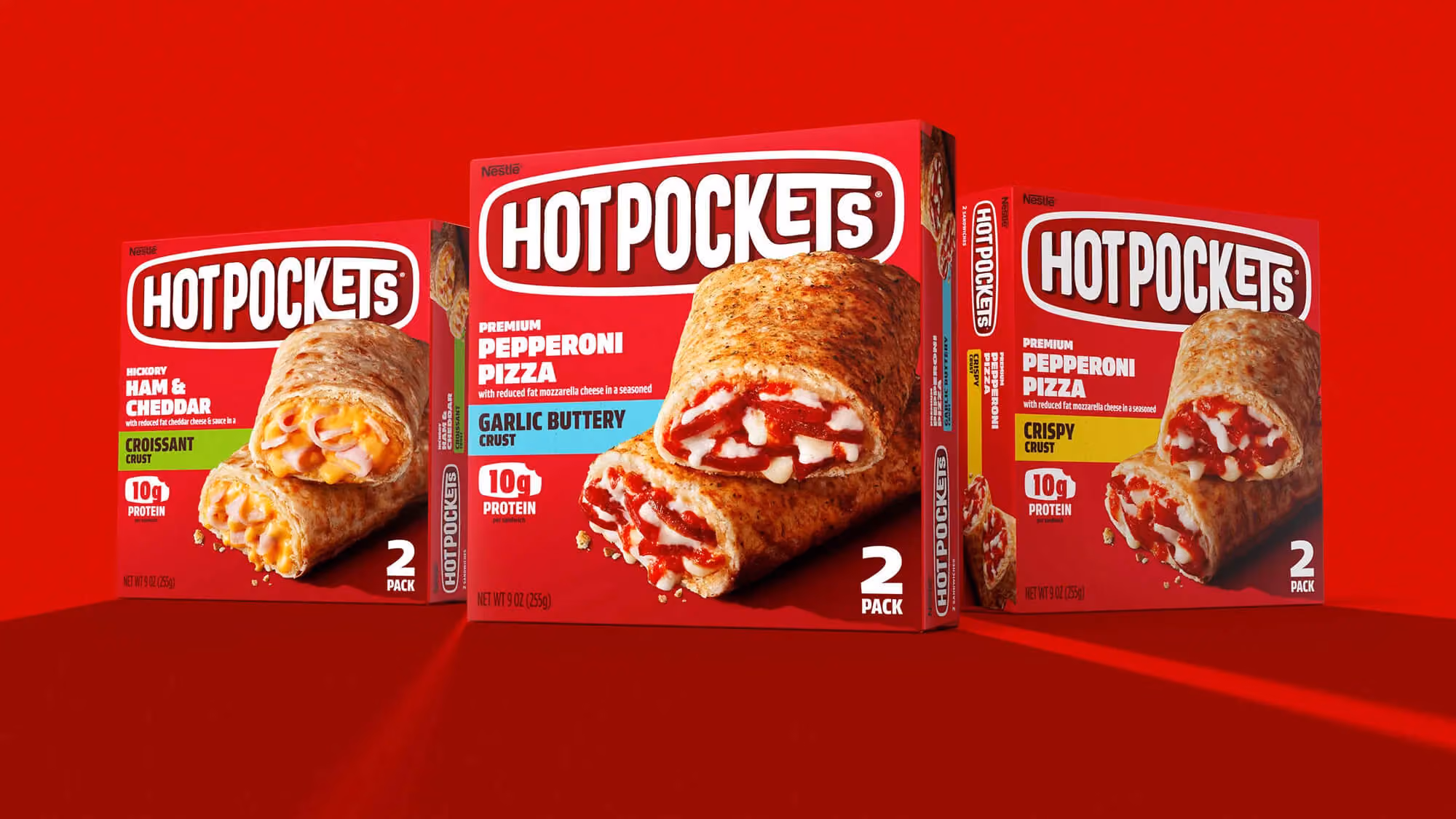 Three Hot Pockets boxes on red: Ham & Cheddar Croissant, Pepperoni Pizza Garlic Buttery Crust, Pepperoni Pizza Crispy Crust.