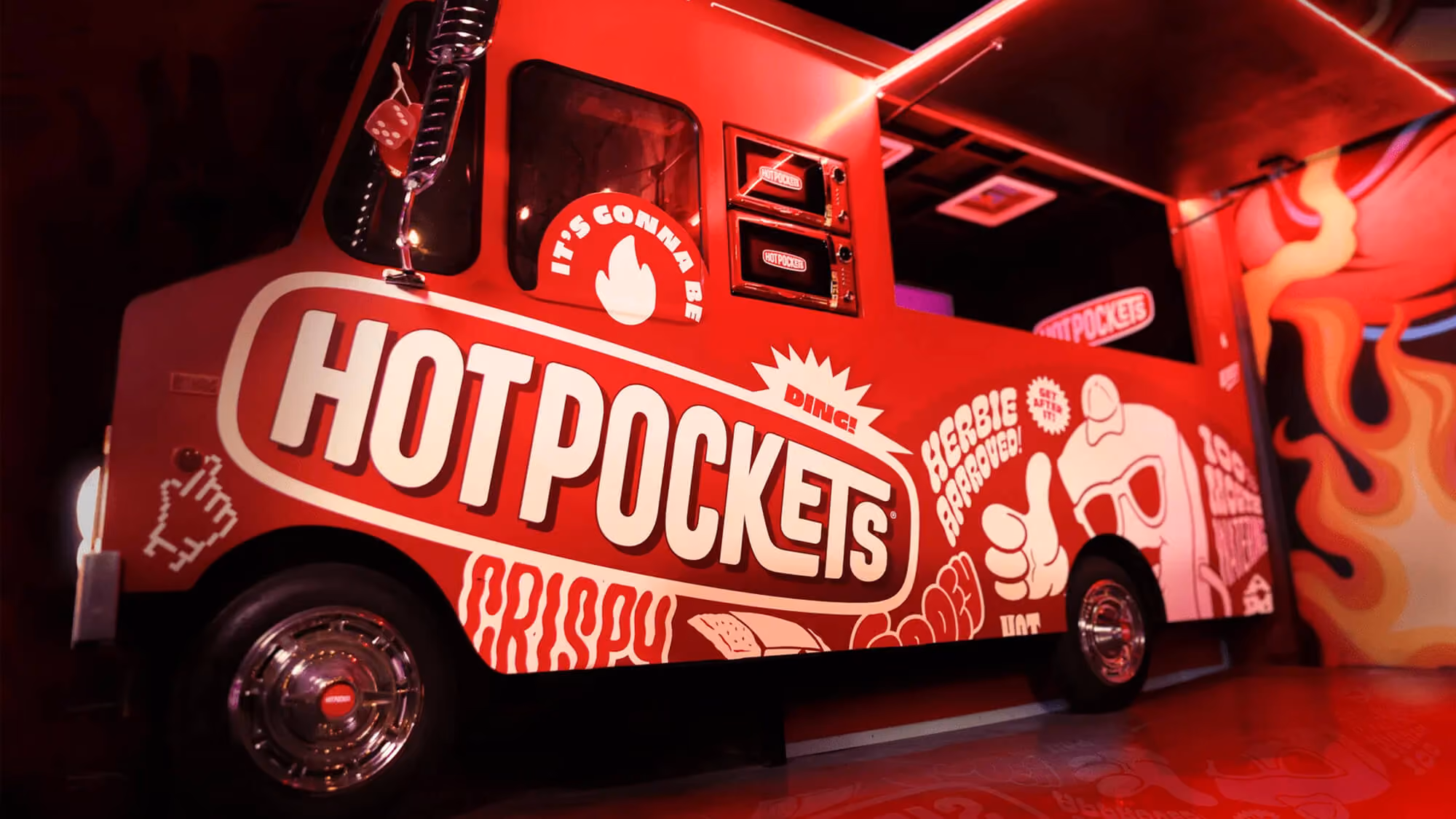 Red Hot Pockets food truck in a dark venue covered in cartoon graphics, mascot art, and 'Crispy / Gooey' lettering.