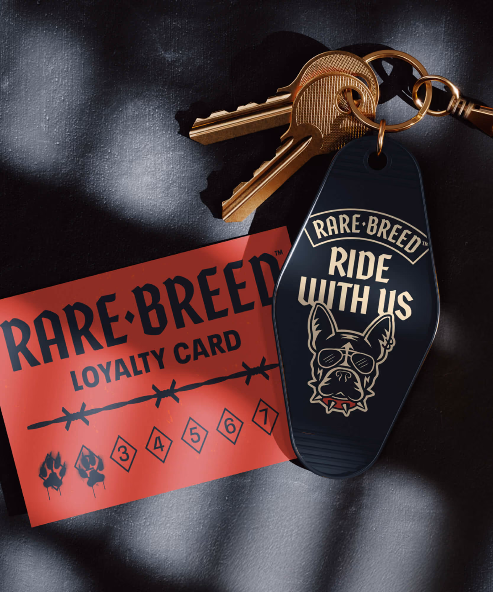 Red Rare Breed loyalty card with paw-print punches beside a black 'Ride with us' keychain fob and brass keys.