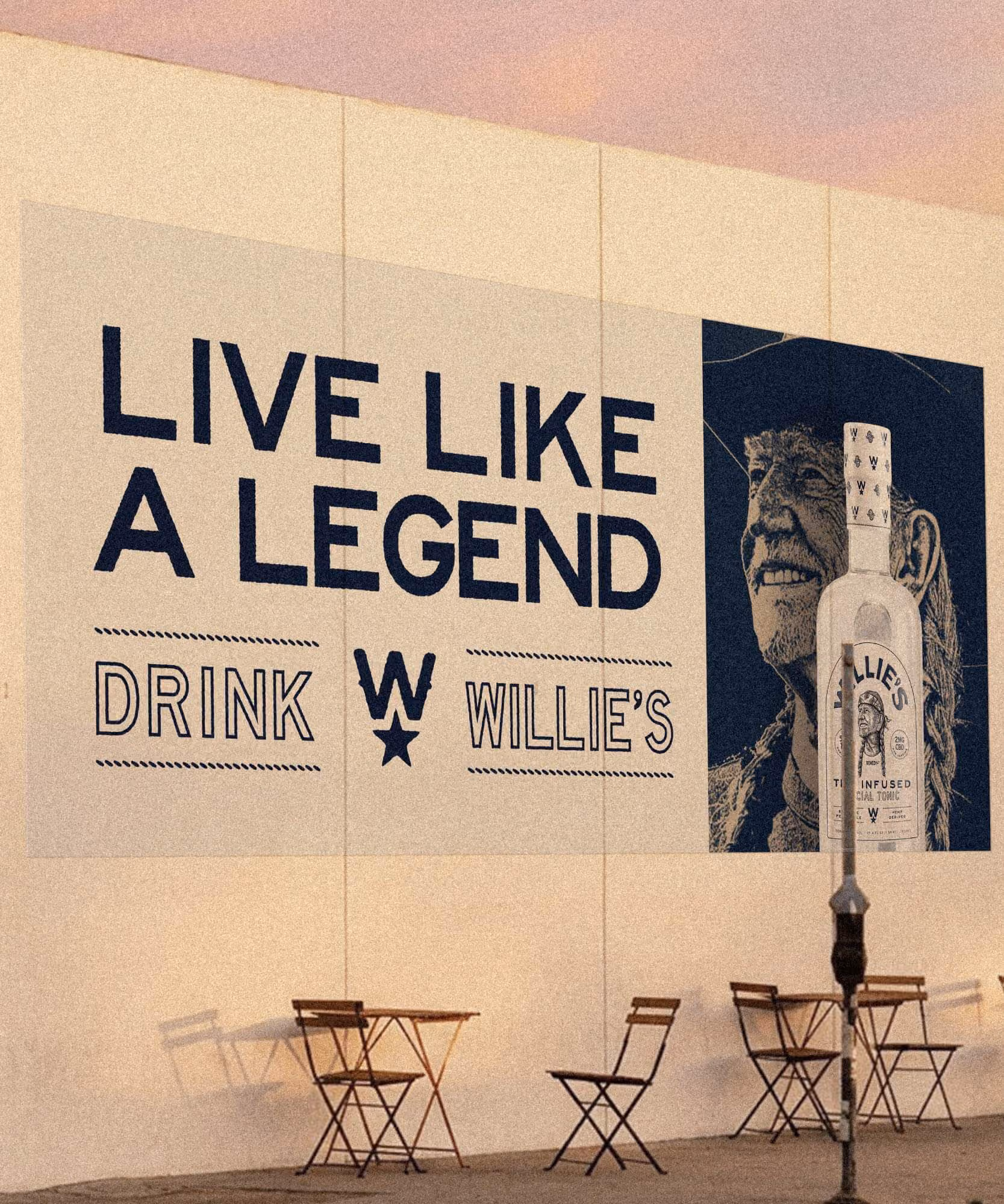 Painted wall ad reading "Live like a legend, drink Willie's" beside a Willie portrait and bottle
