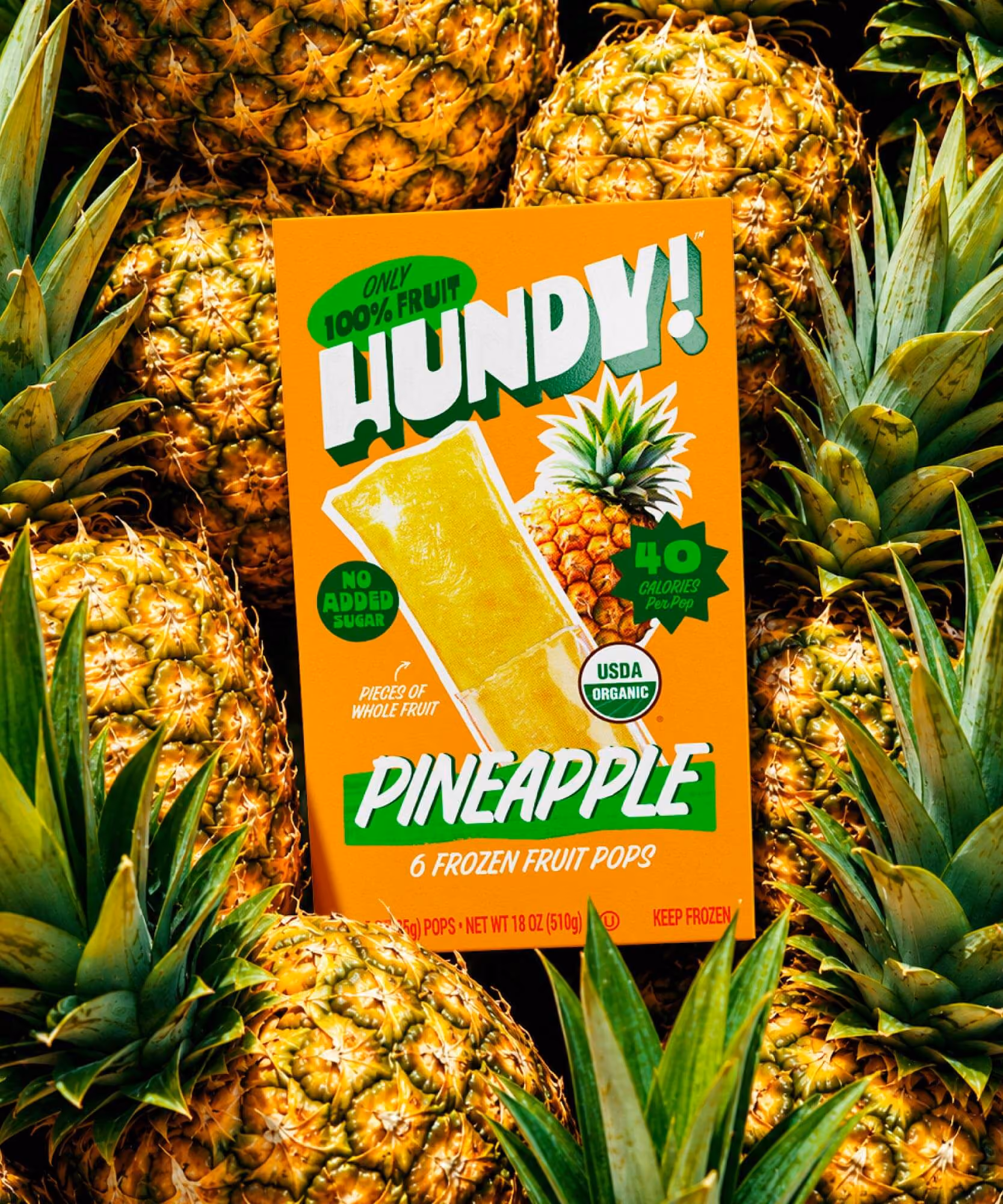 Orange "PINEAPPLE" carton resting on a bed of whole pineapples, badged "40 CALORIES Per Pop"