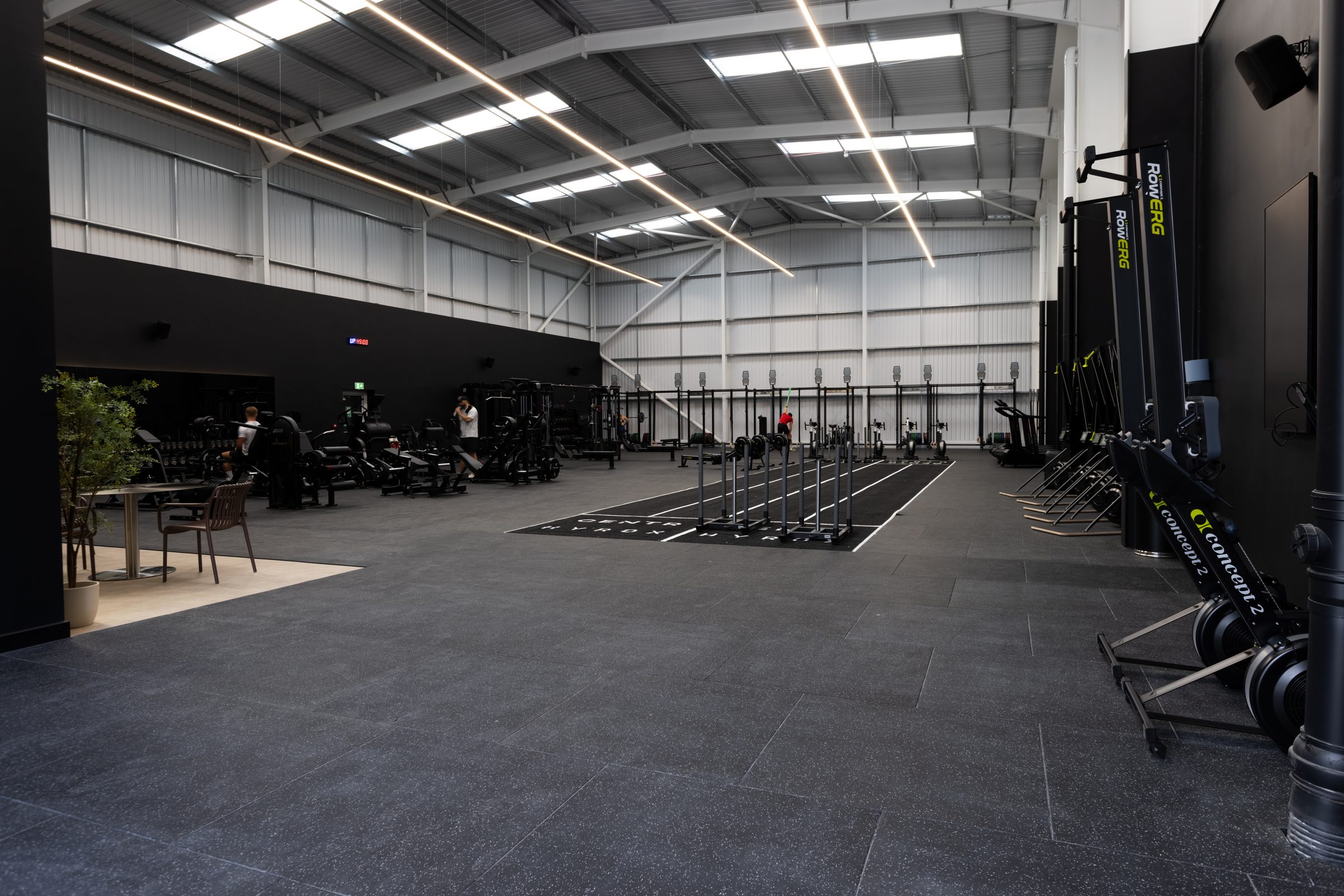 The main training floor at Atlas Training Club in Adlington — HYROX sled track, Concept2 rowers and ski ergs, strength rig and free weights area