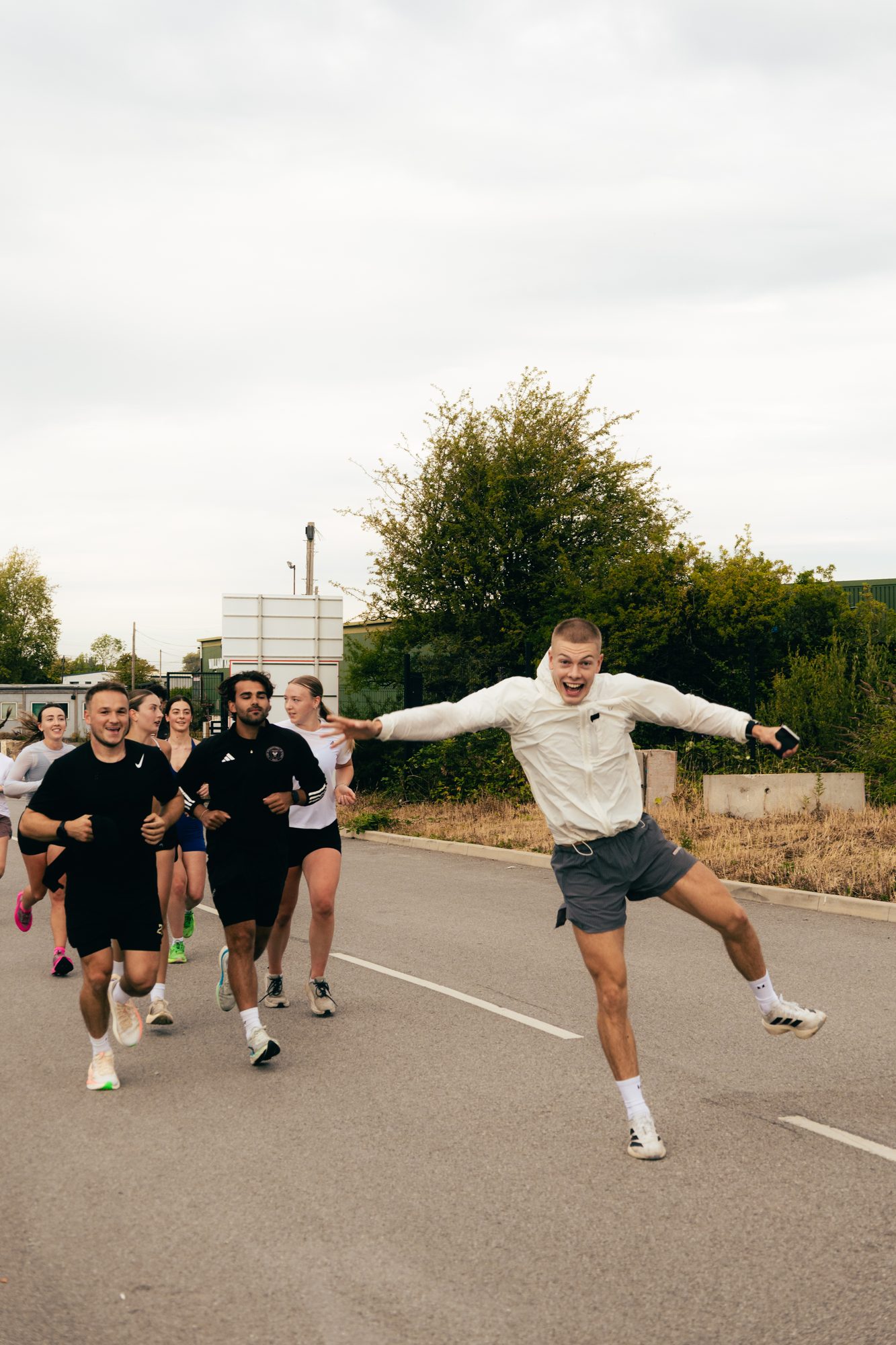 Atlas Training Club run club out on the road in Adlington — a runner leaping with arms outstretched ahead of the pack