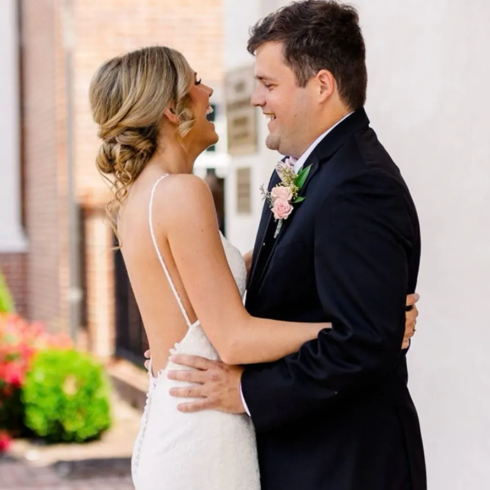 Bride with romantic low bun and loose curls embracing groom in downtown Greenville NC, styled by Dayln Faith Hair and Beauty