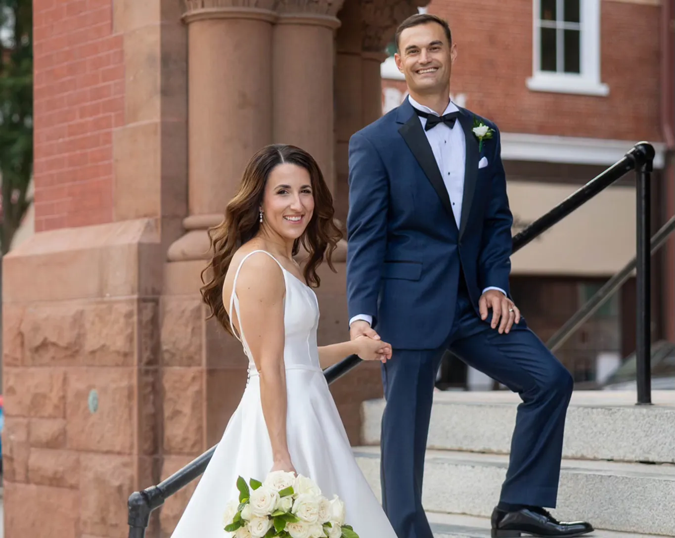 Bride with flowing loose curls down hairstyle on the steps of a historic Raleigh NC venue, styled by Dayln Faith Hair and Beauty