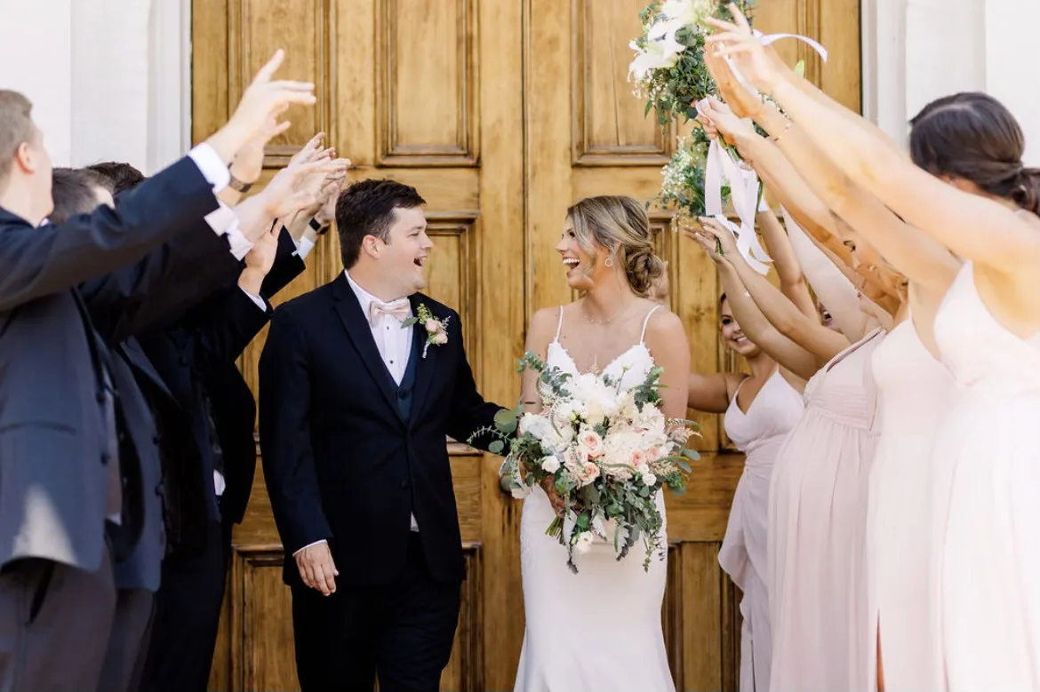 ride with romantic textured updo celebrating with wedding party in front of wooden doors in Greenville NC, styled by Dayln Faith Hair and Beauty