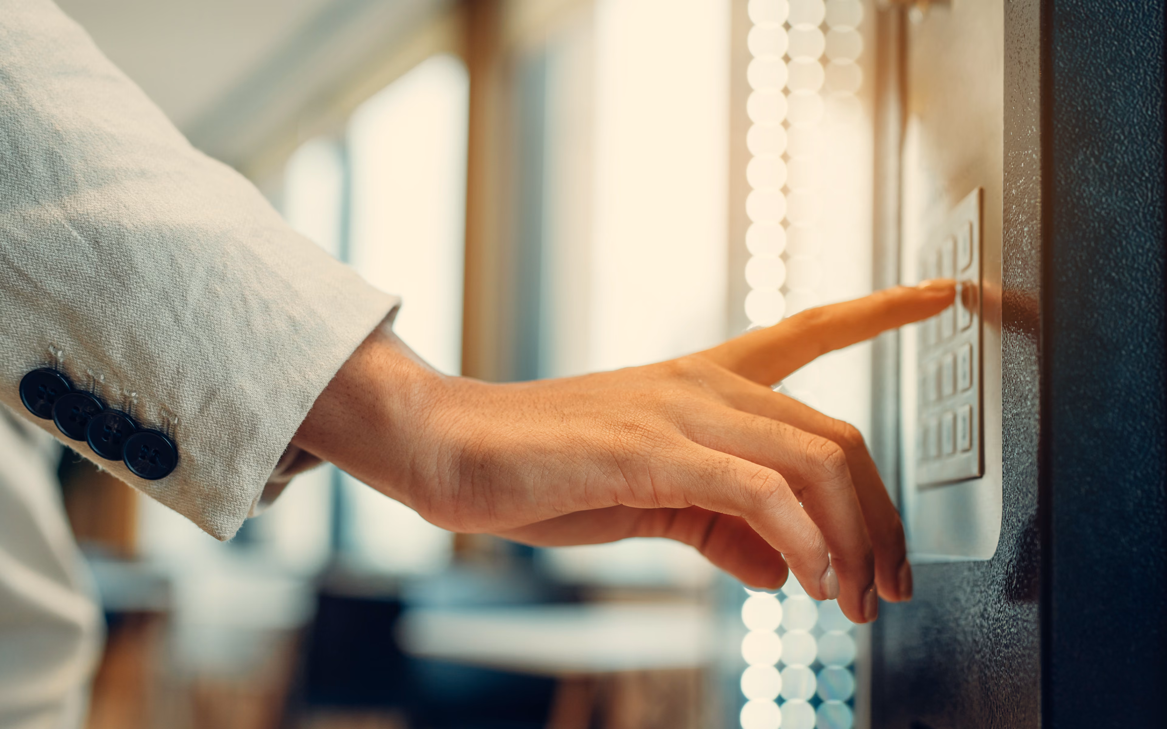 Hand pressing a button on a vending machine keypad with a blurred indoor background.
