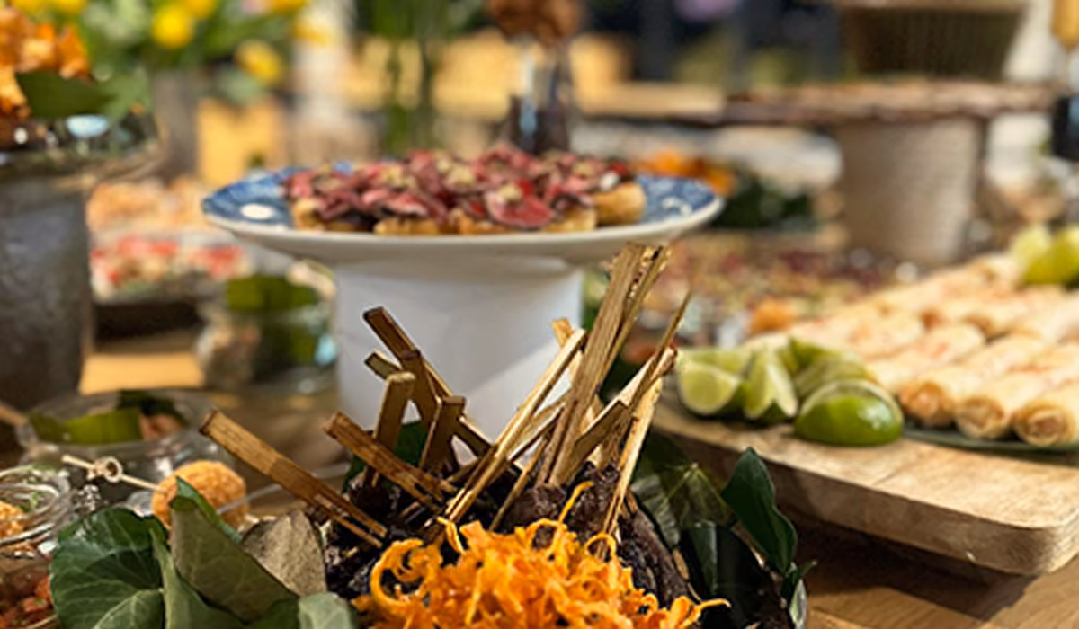 Close-up of skewered grilled meat with garnish on a buffet table with other appetizers.