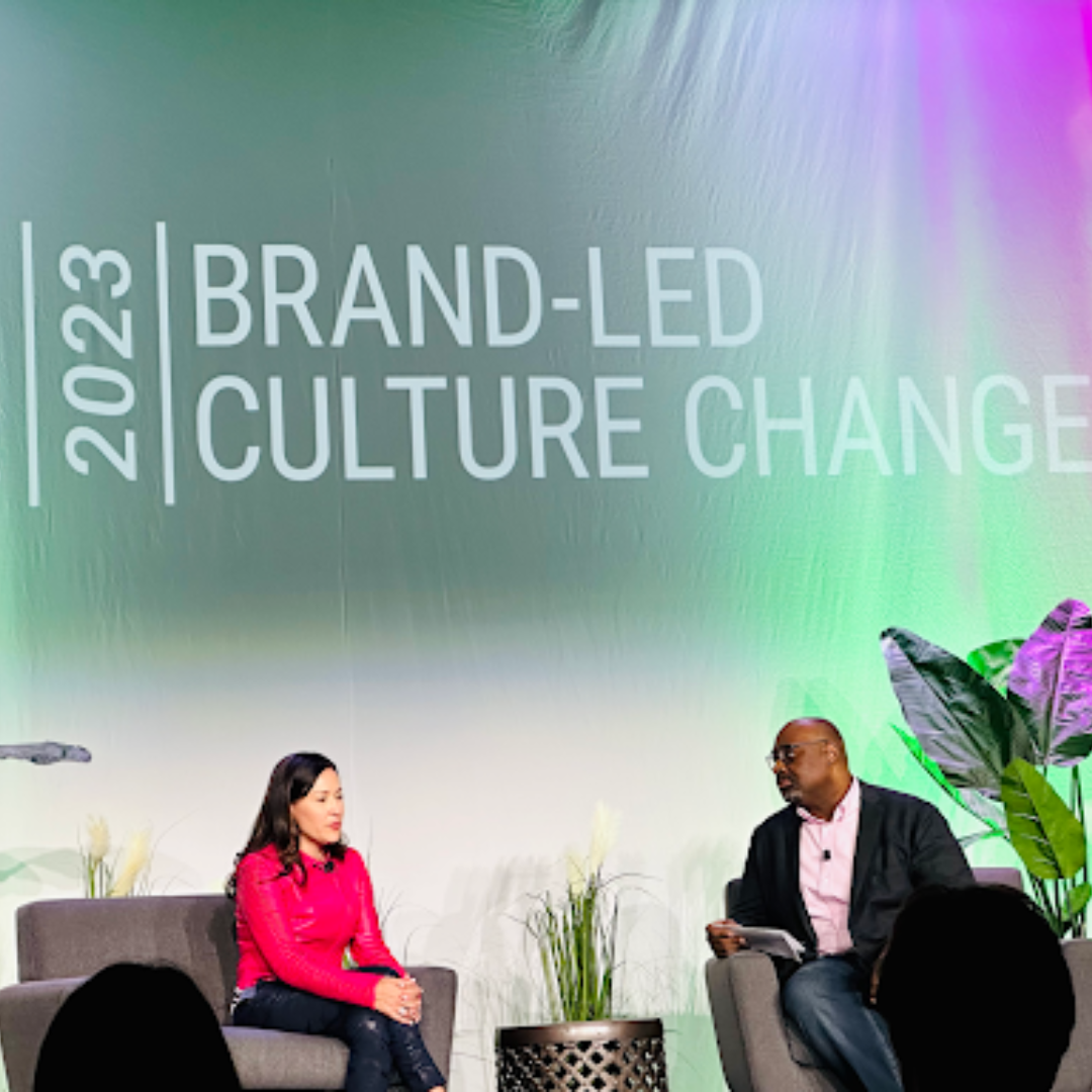 Mary Jane Melendez and Samuel Monnie seated on stage in front of the Brand-Led Culture Change backdrop