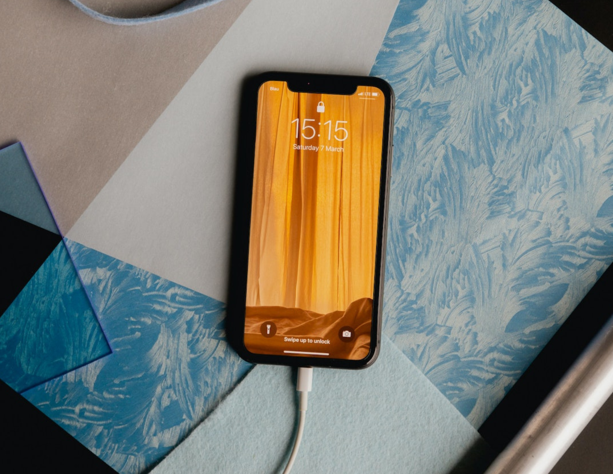 Phone lying on a patterned desk surface showing its lock screen at 15:15