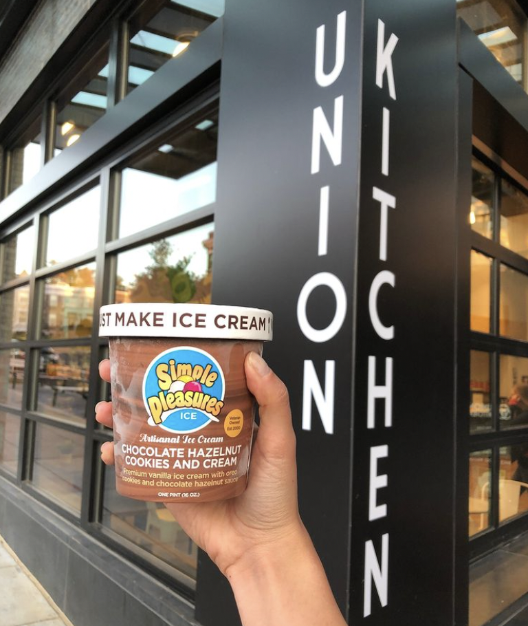 Simple Pleasures chocolate hazelnut cookies and cream ice cream pint held outside Union Kitchen