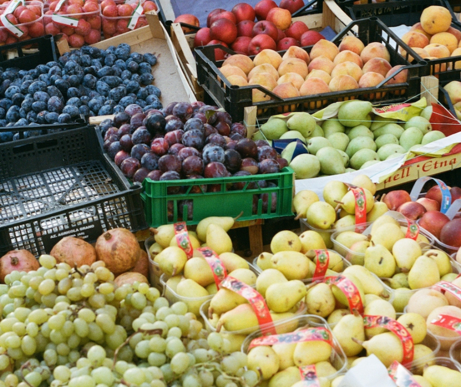 Crates of plums, peaches, pears and grapes at an outdoor market