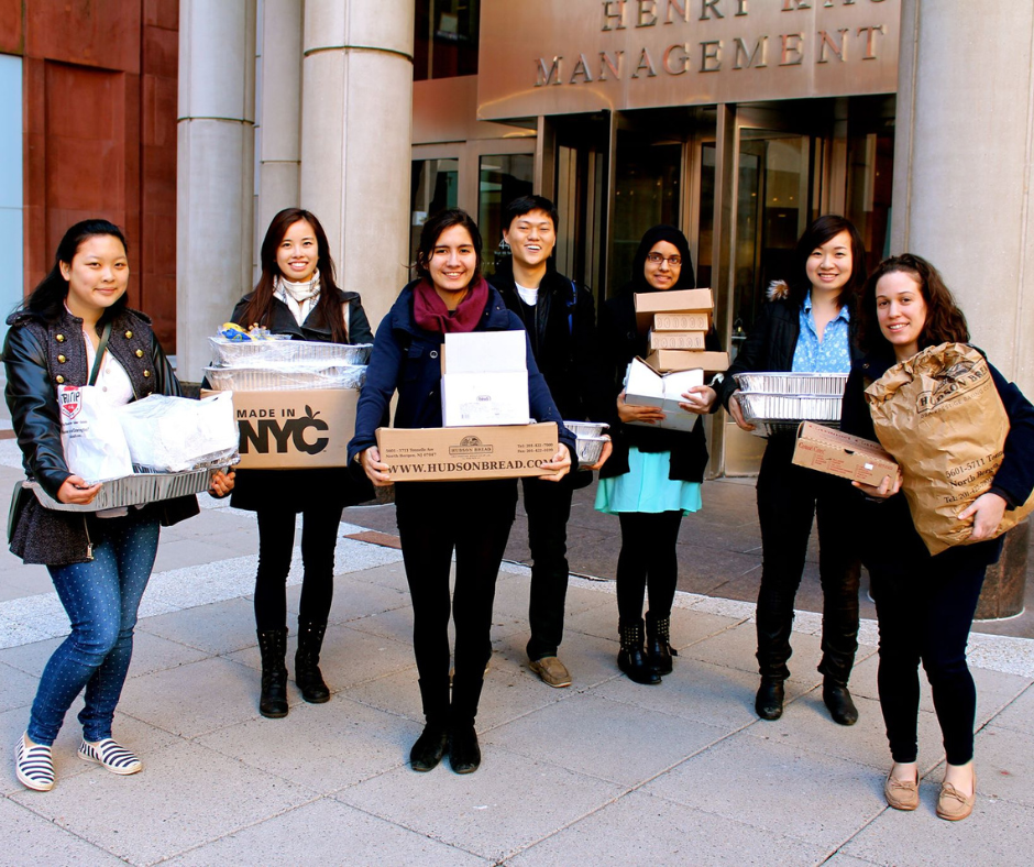 Students holding trays and boxes of recovered food outside a campus building