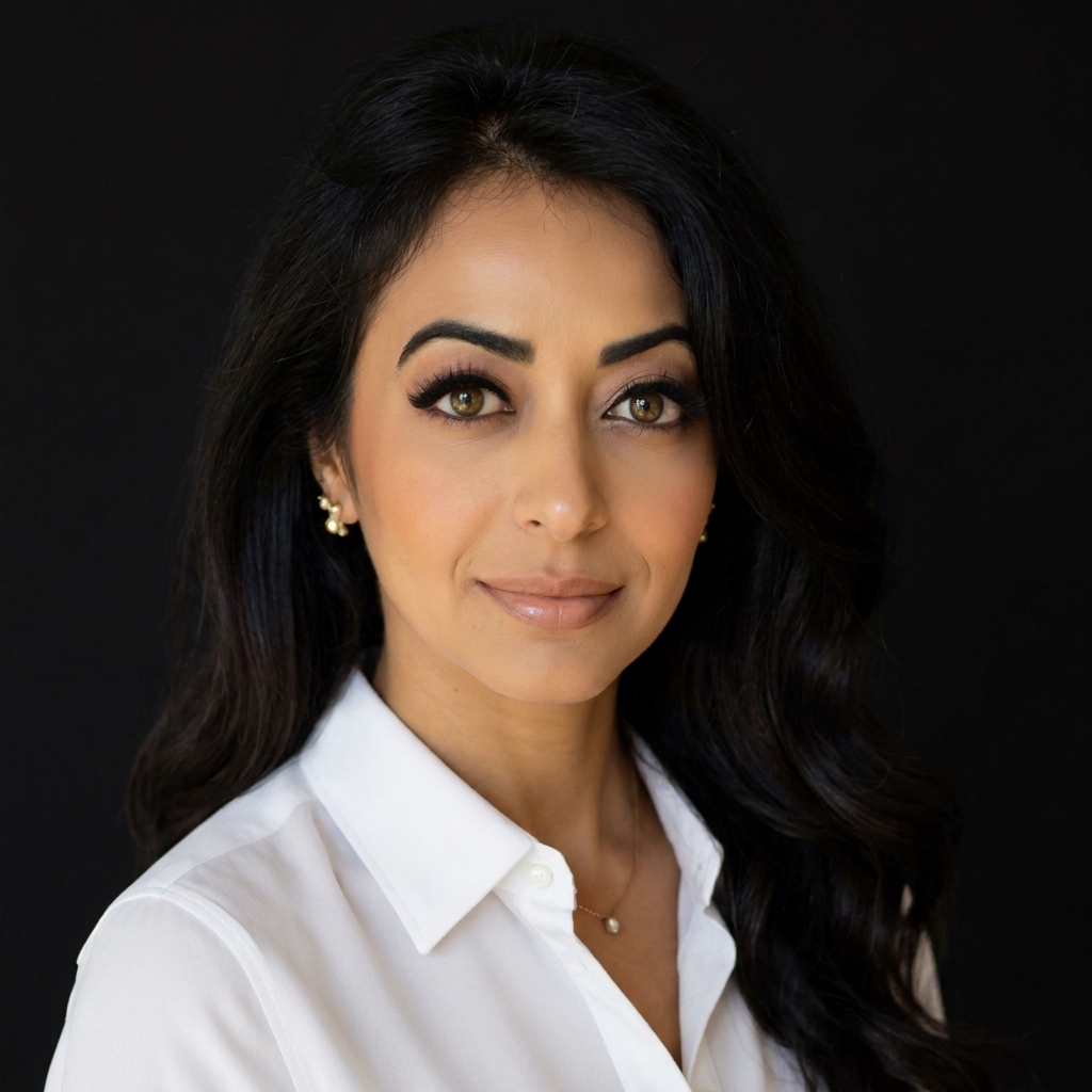Portrait of a woman with dark hair wearing a white collared shirt and gold earrings against a black background.