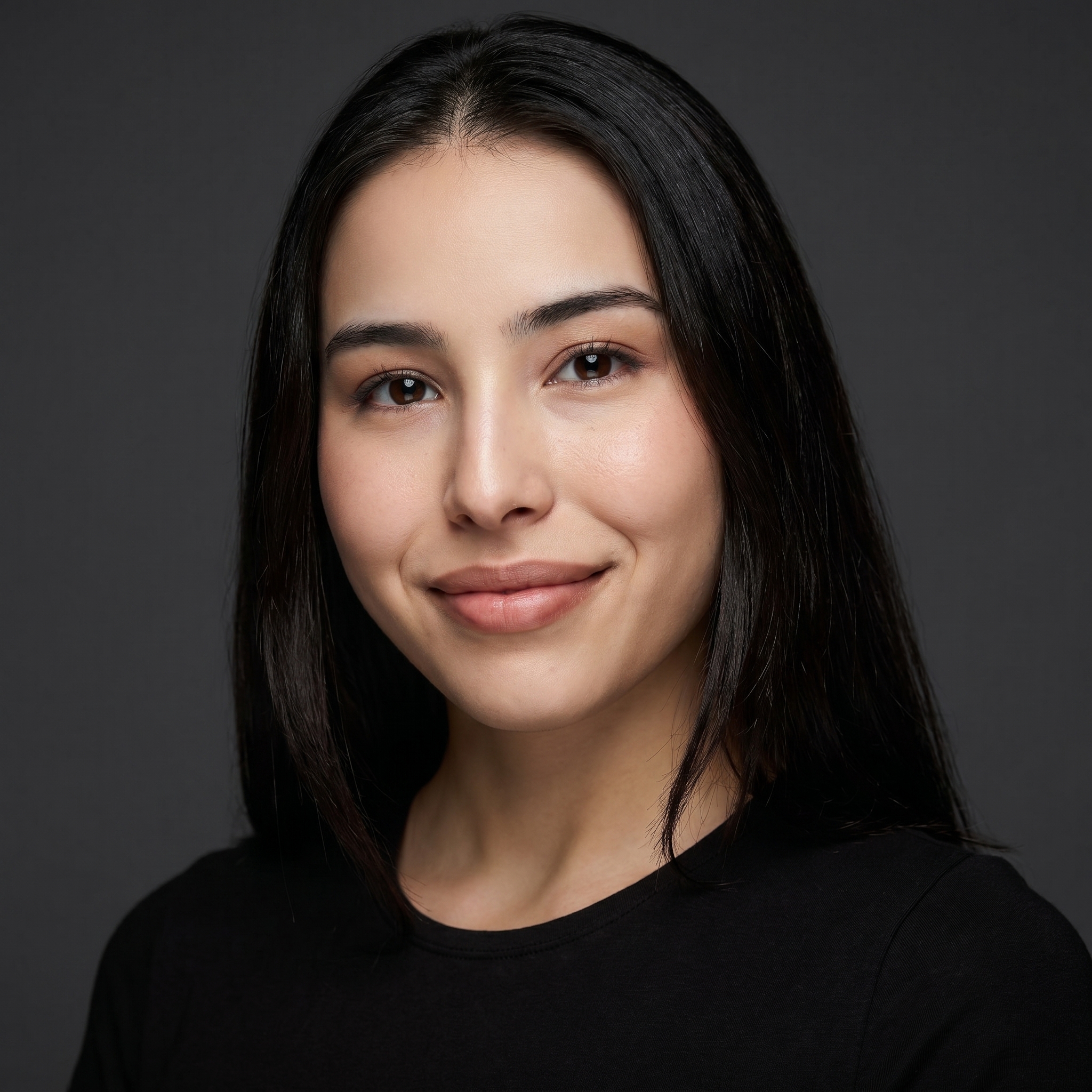 Young woman with straight dark hair wearing a black top, looking calmly at the camera against a black background.