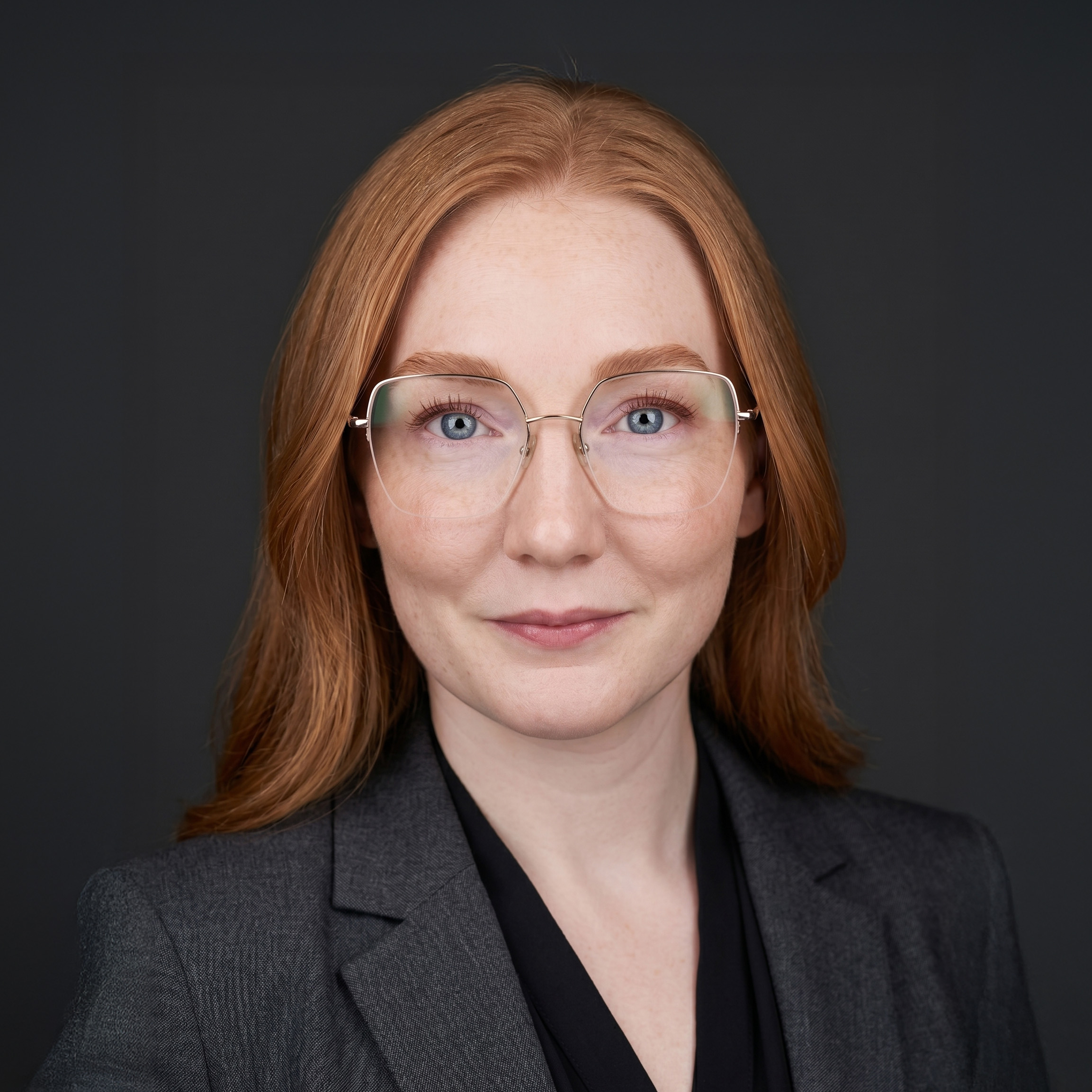 Portrait of a woman with wavy brown hair, blue eyes, wearing a white button-up shirt against a black background.