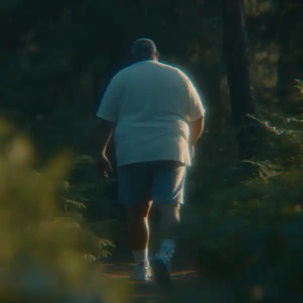 Overweight, older man walking trough the woods.