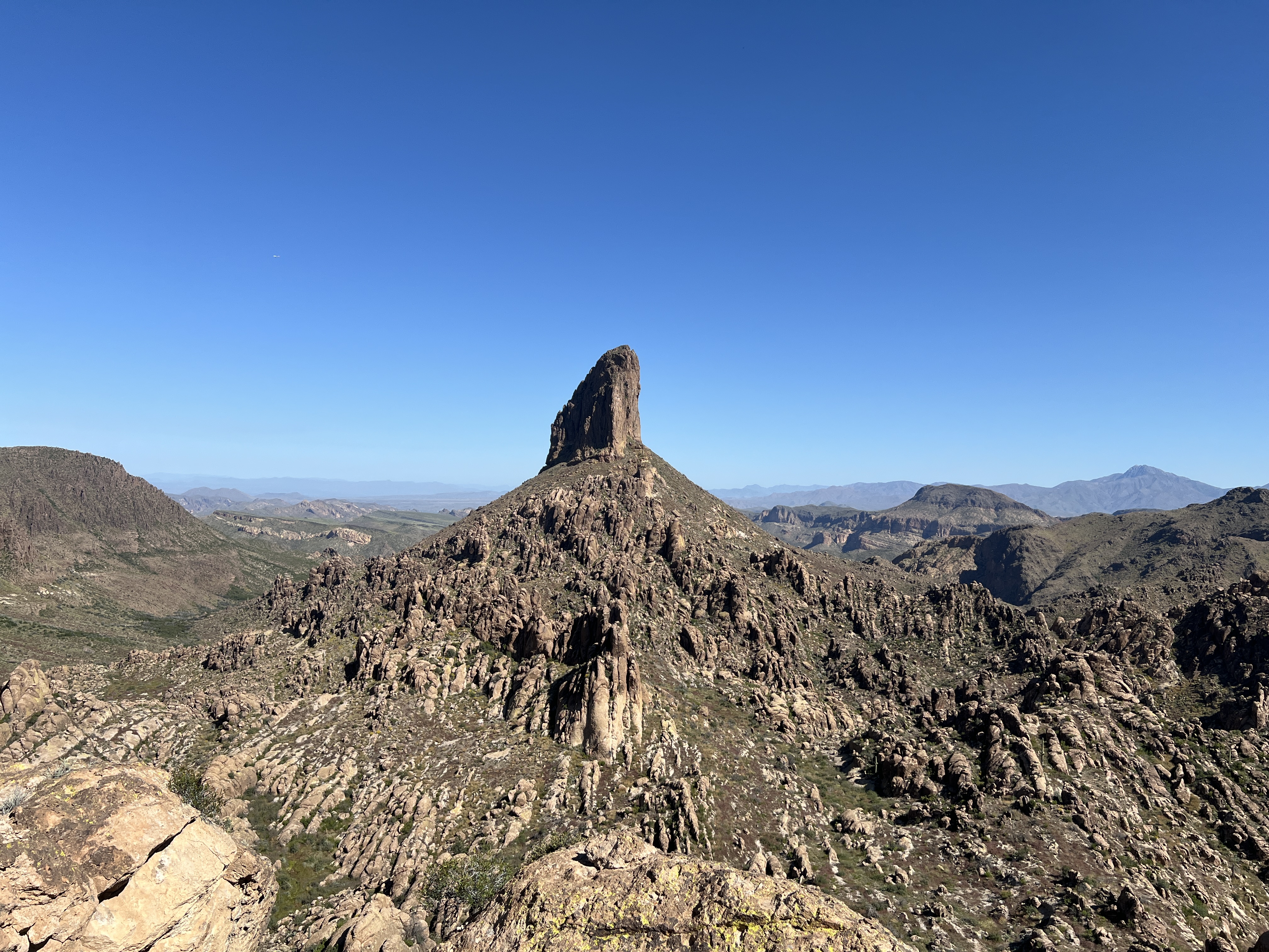 Rocky Arizona desert landscape with a prominent stone spire beneath a clear blue sky