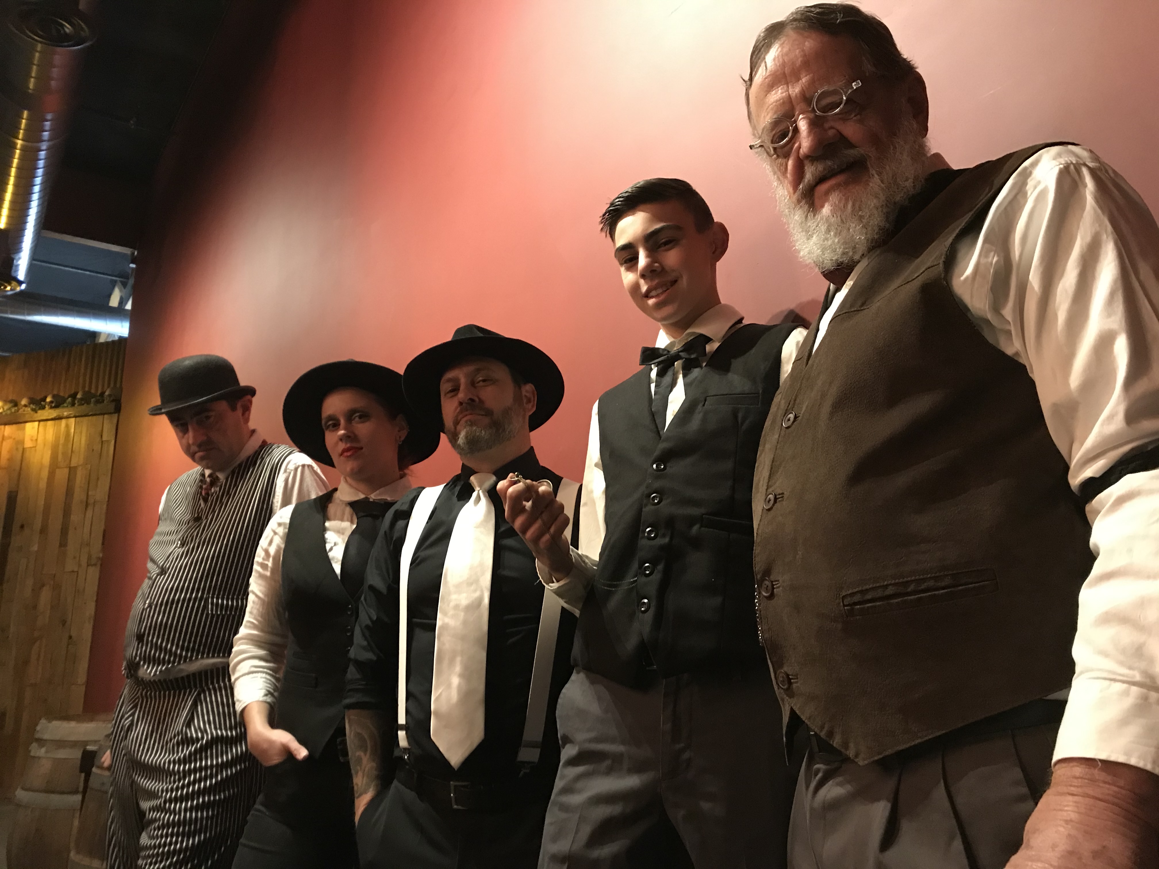 Five people in vintage Western attire gathered inside the Bone Haus taproom