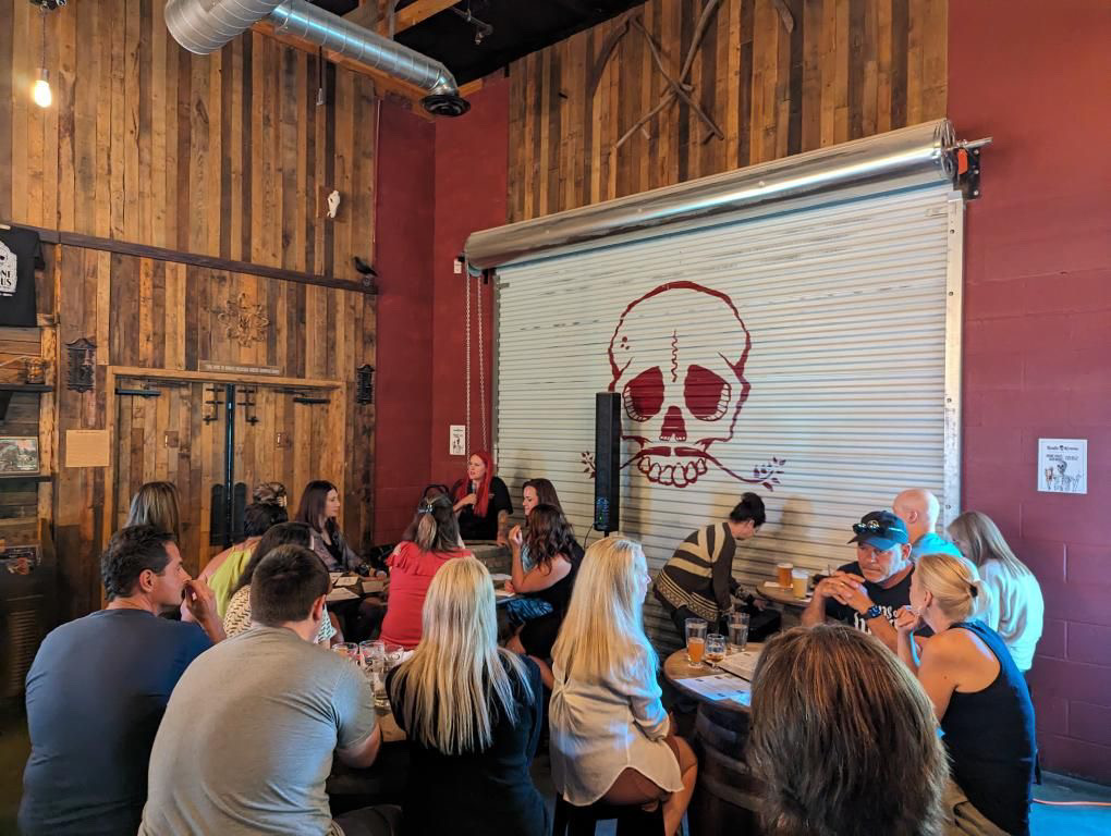 Guests gathered around tables in the Bone Haus taproom beneath the signature skull mural