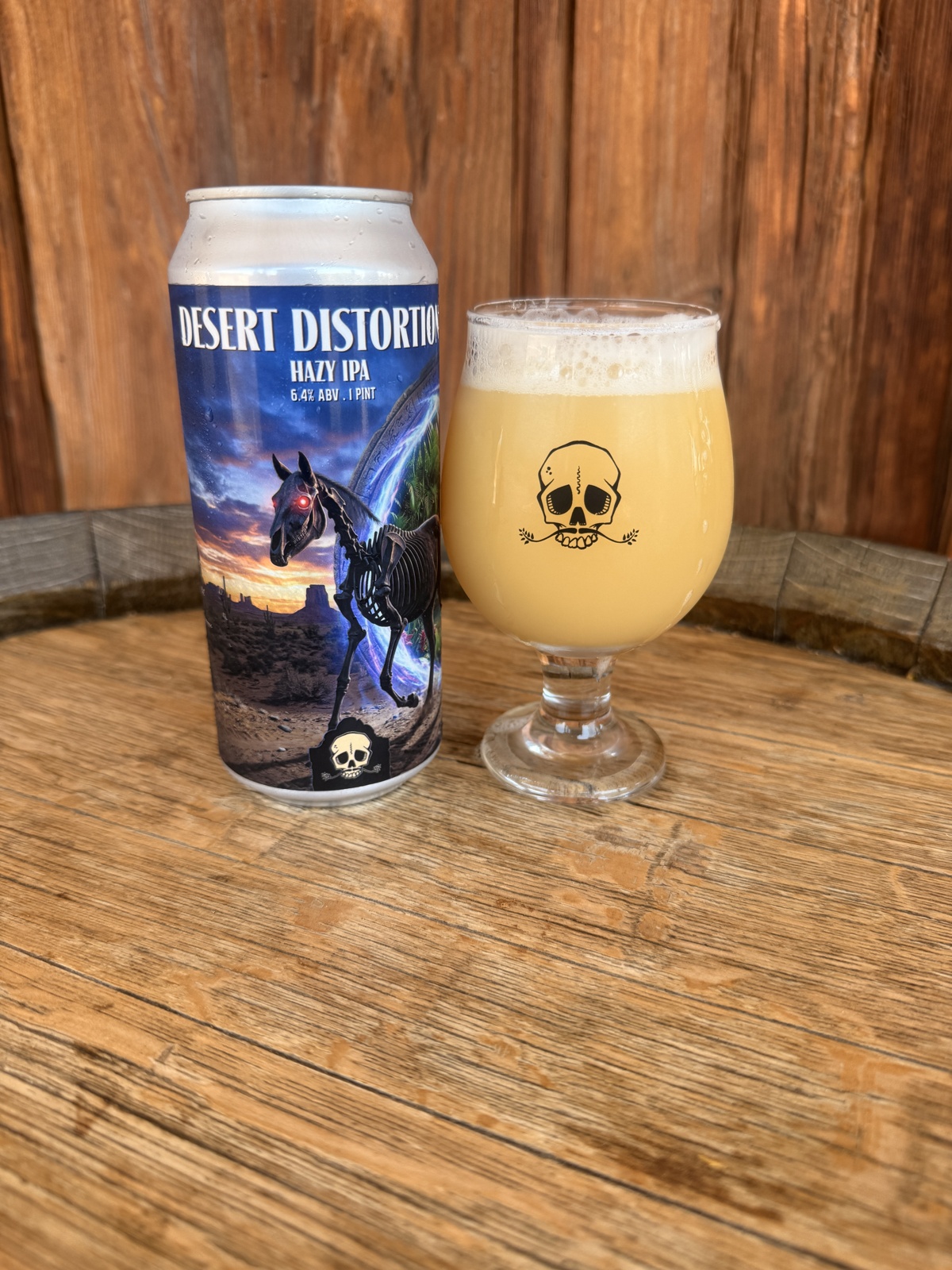 Desert Distortion Hazy IPA can beside a Bone Haus skull-logo glass of beer on a wooden table