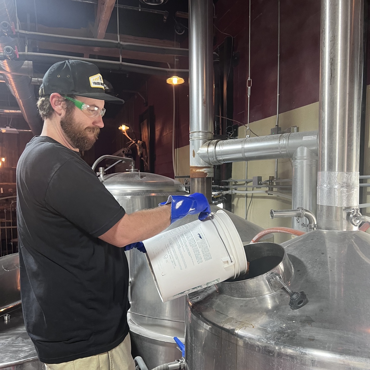 Kerry McLelland, Bone Haus Head Brewer, working at a brewing vessel in the brewhouse
