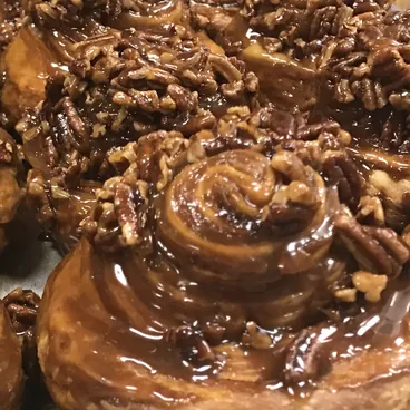 Tray of assorted golden-brown pastries including danishes and muffins on a wooden surface.