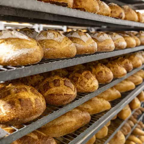 Wooden bakery display case with glass doors holding assorted pastries and croissants.