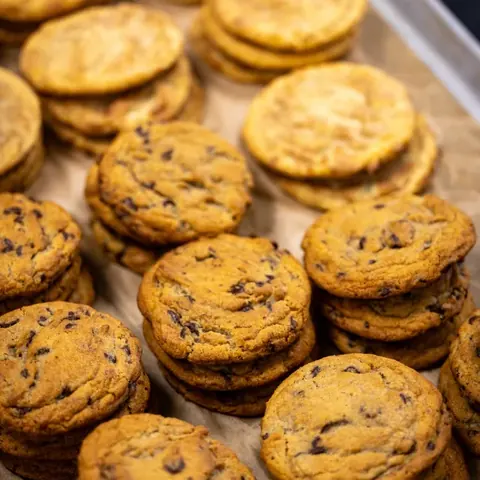 Stacks of golden brown chocolate chip cookies arranged on a parchment-lined tray.