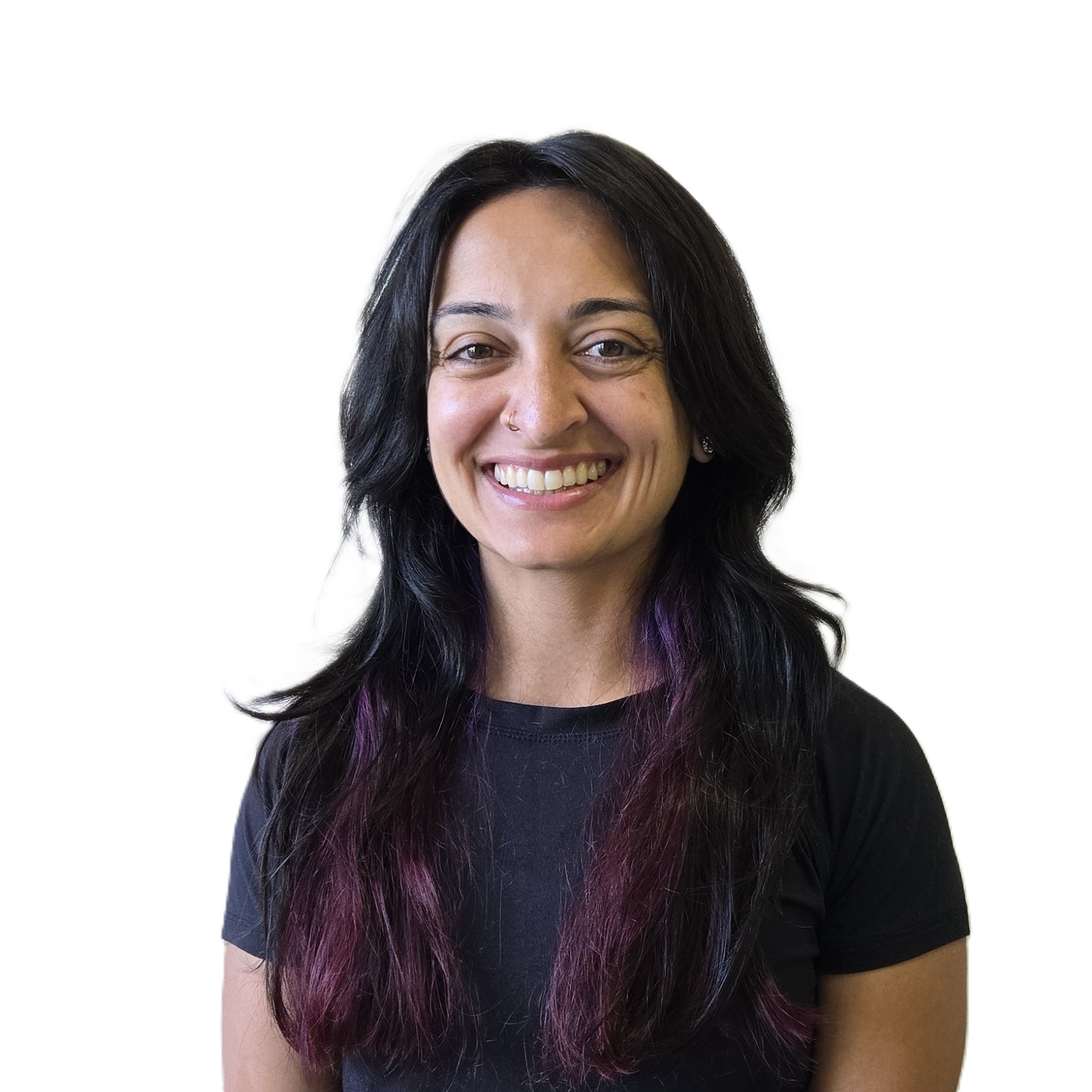 Smiling woman with long black hair dyed purple at the ends wearing a black shirt against a plain wall.