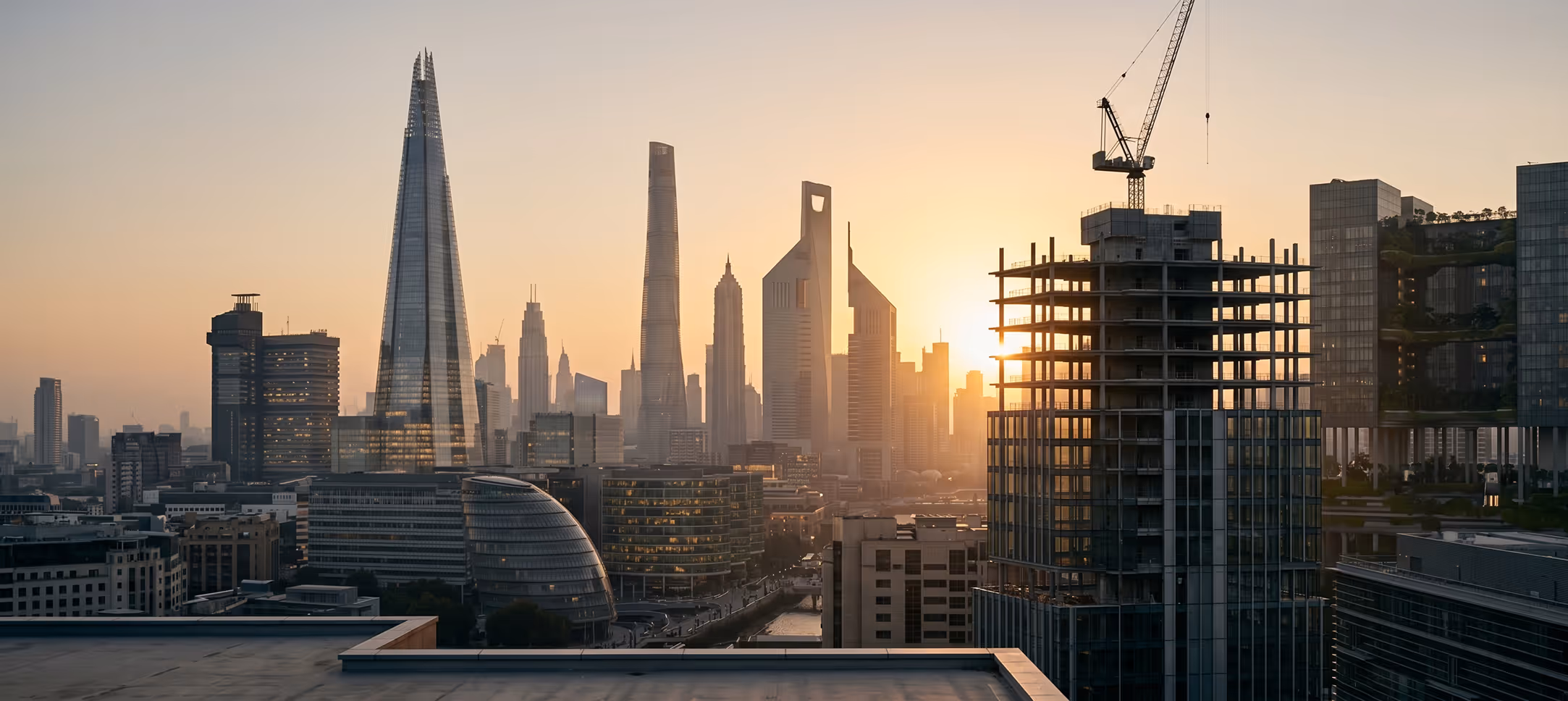 City skyline at sunset featuring modern skyscrapers and a building under construction with a crane.