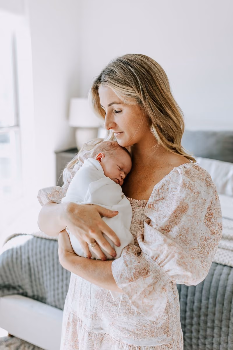 Mother gently holding her newborn at home