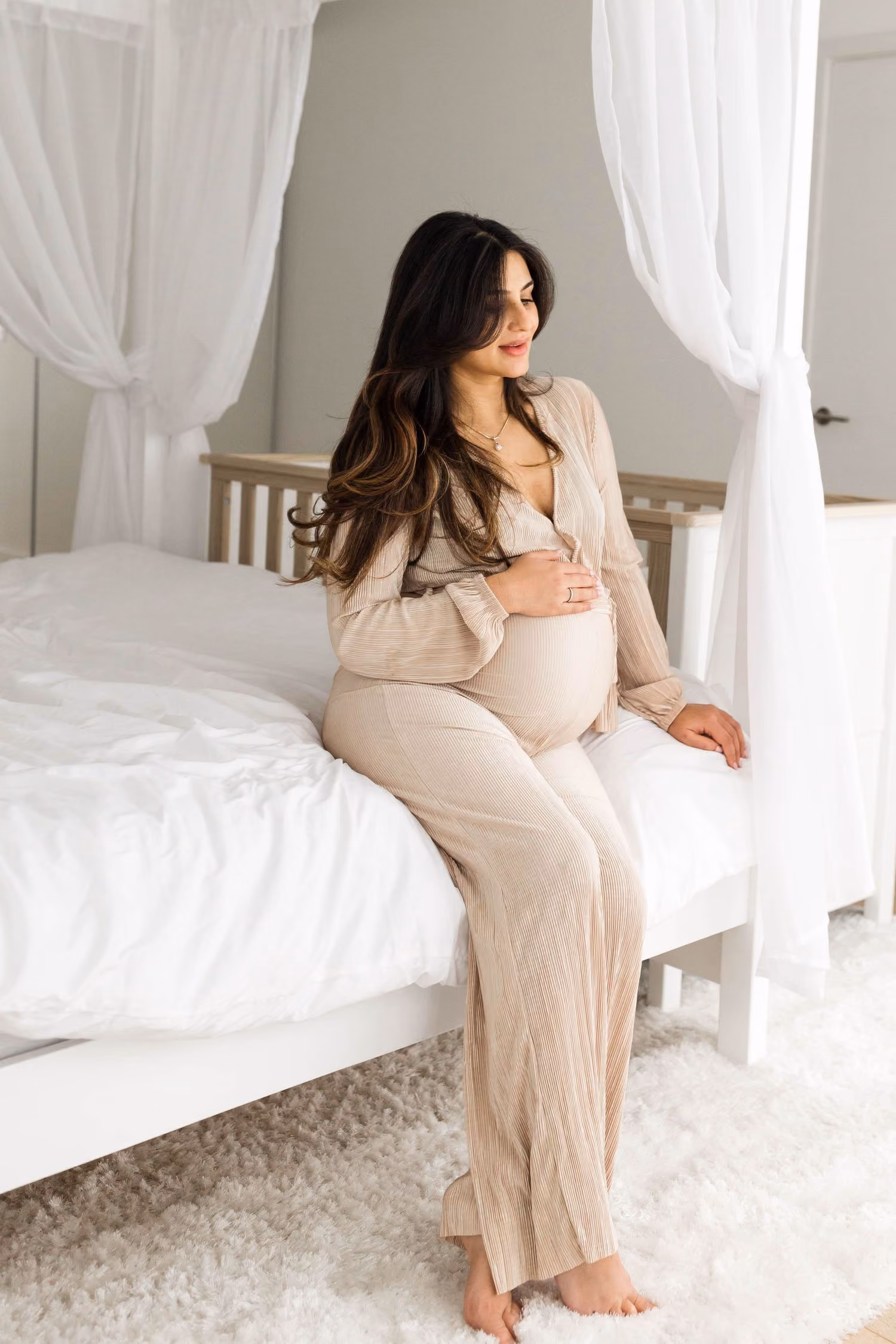 Pregnant mother resting in a bright neutral bedroom