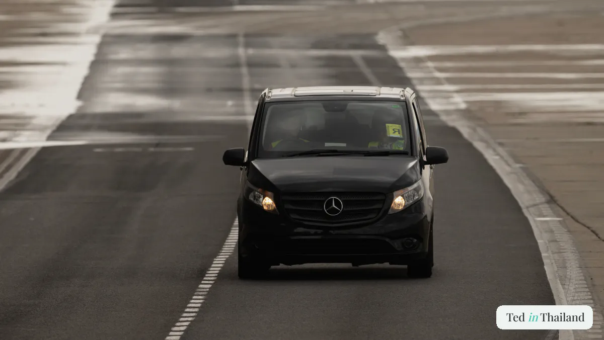 A black private transfer minivan on the airport apron, the pre-booked airport-to-hotel option on Koh Samui