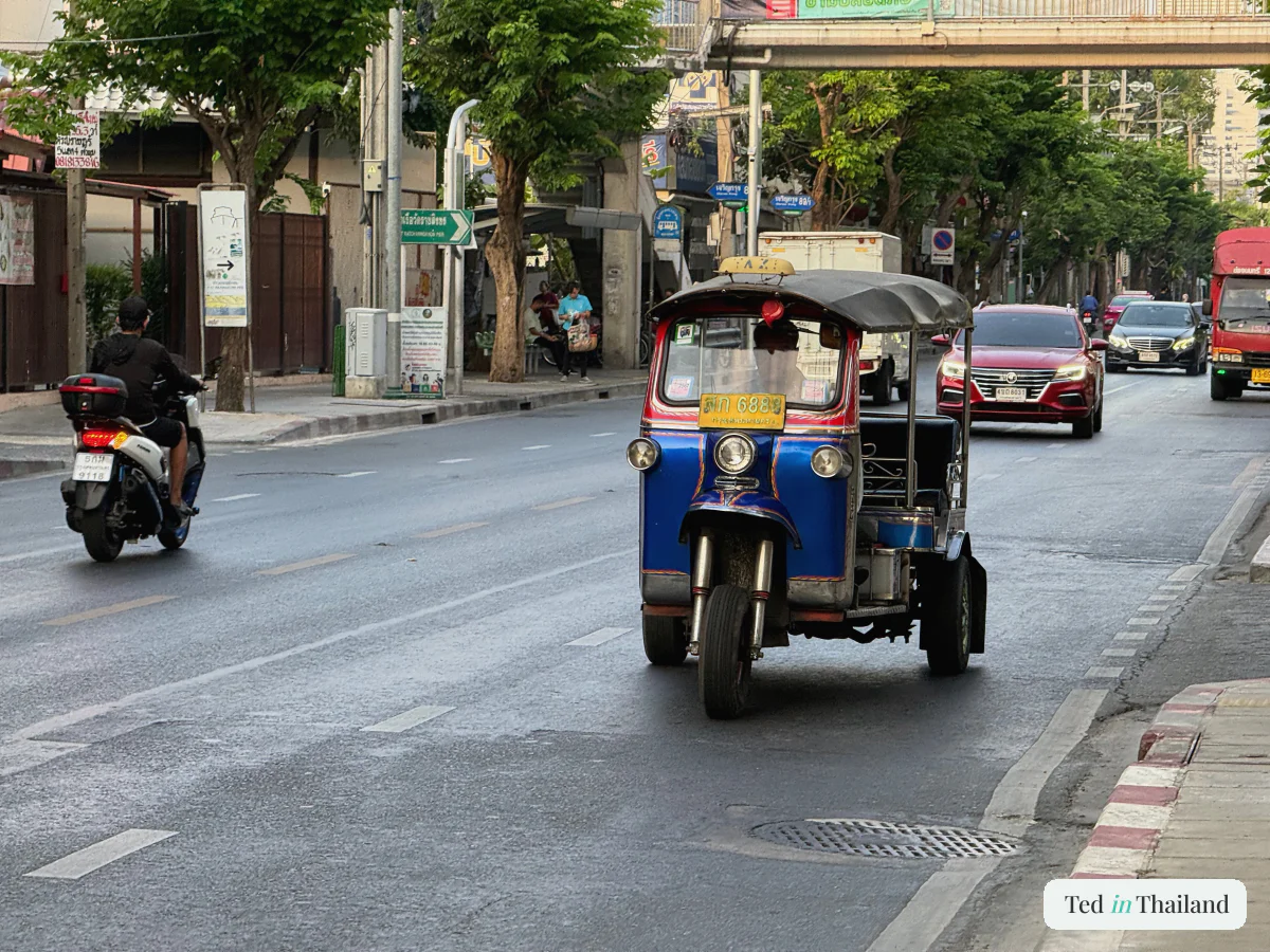 A tuk-tuk and scooter on a busy Koh Samui street, a reminder to check travel insurance covers medical treatment