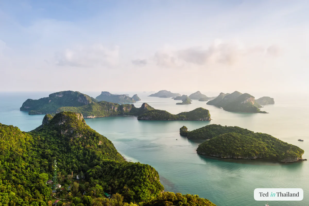 Golden-hour light over the forested islands of Ang Thong National Marine Park fading into a hazy horizon near Koh Samui
