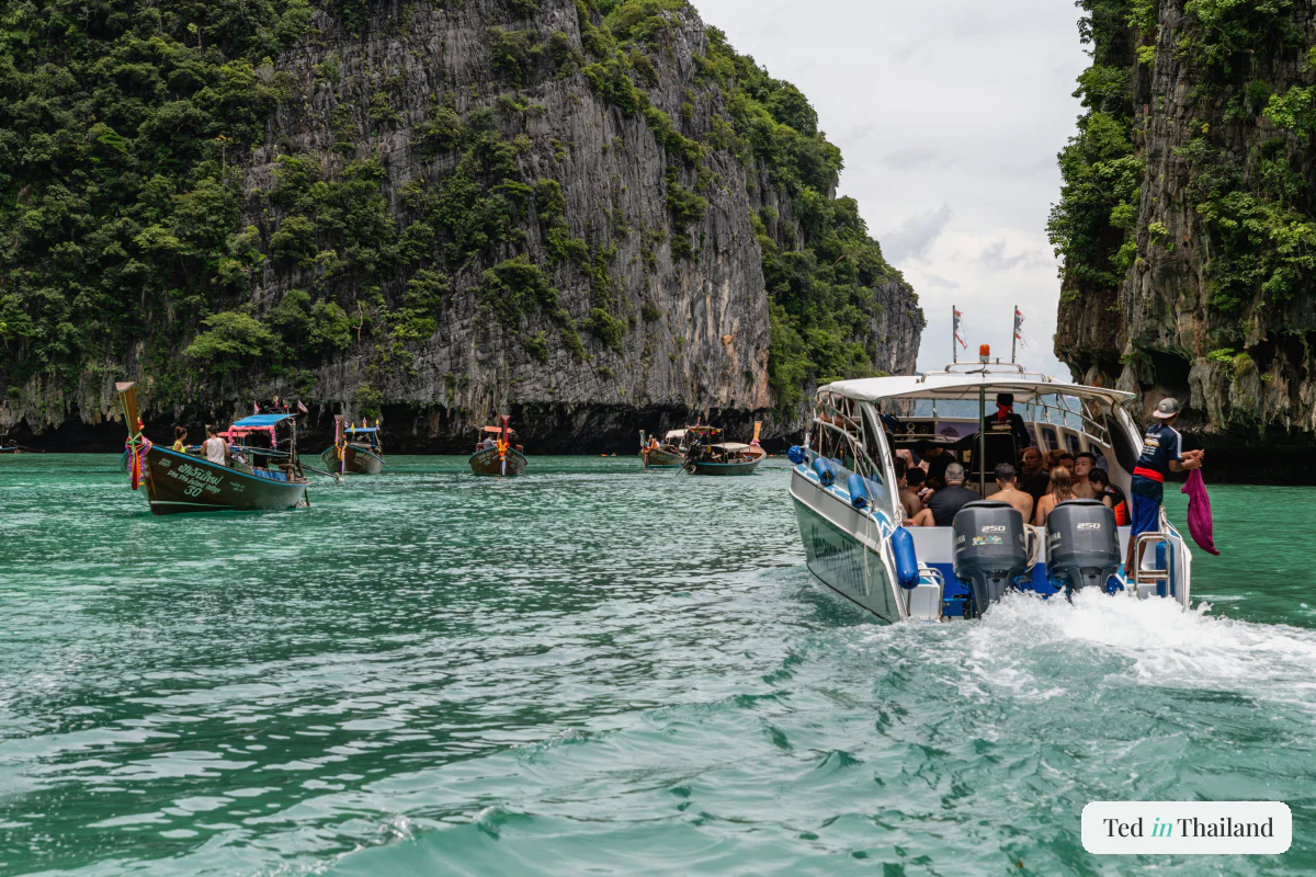 A speedboat packed with day-trippers threading between steep jungle cliffs on an island tour from Koh Samui