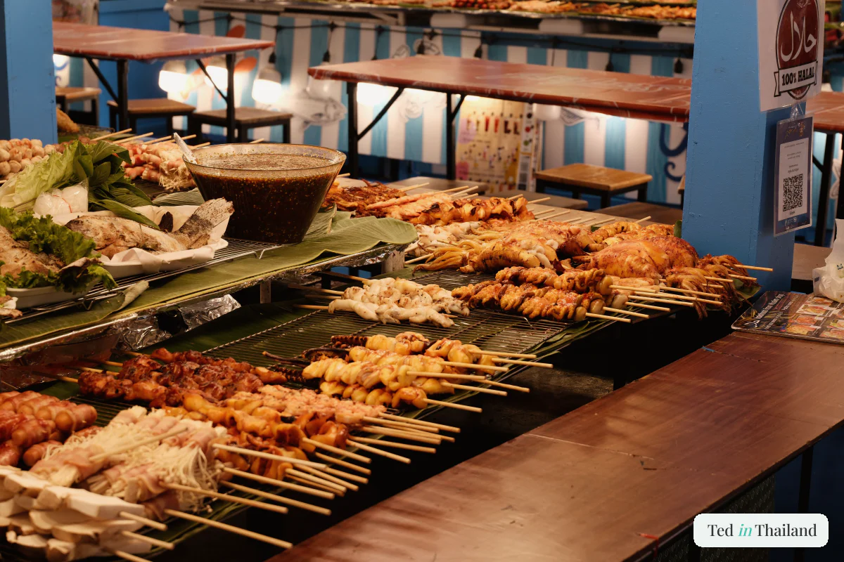 Rows of grilled pork moo ping skewers sizzling over coals at a Chaweng night-market food stall on Koh Samui