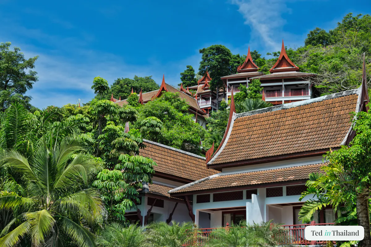 Traditional Thai-style resort villas with tiered tiled roofs set in tropical jungle, typical Koh Samui accommodation