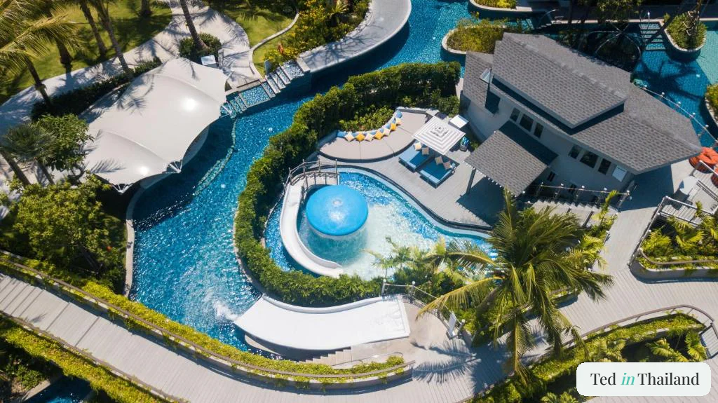 Aerial view of the winding lazy river, children's pool and blue waterslide at Melia Koh Samui in Choeng Mon