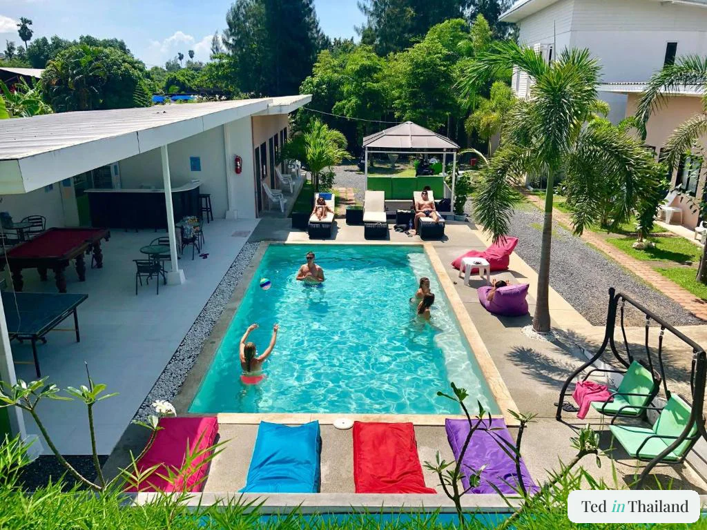 Guests in the pool surrounded by bean bags, a poolside bar and pool table at Samui Backpacker Hotel in Bangrak