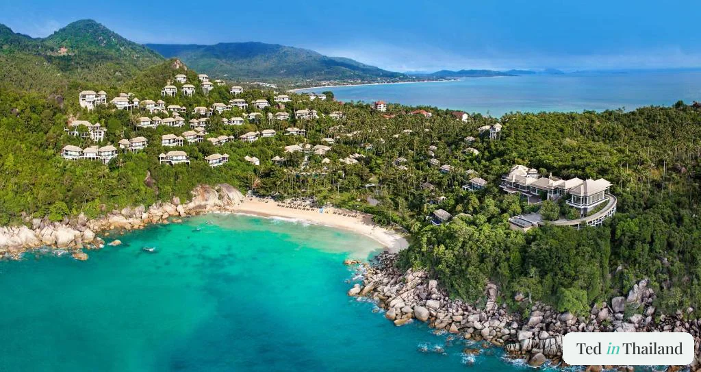 Aerial view of Banyan Tree Samui's tiered hillside villas stepping down through jungle to a private cove