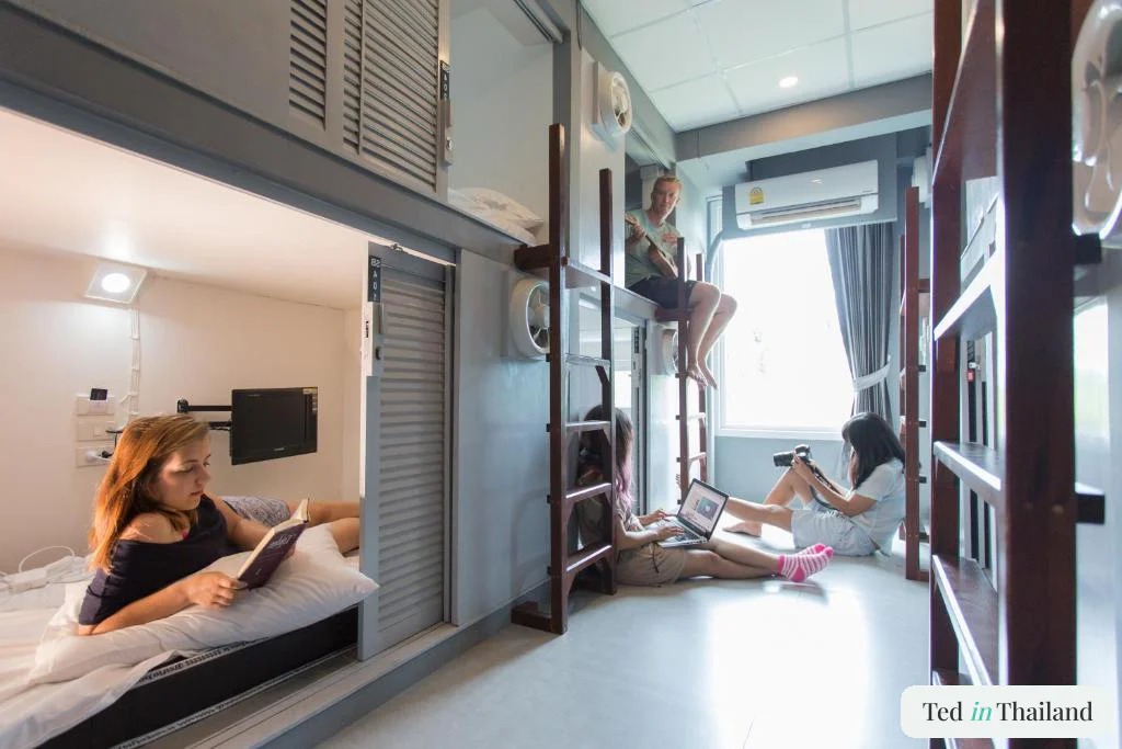 Backpackers reading and working on laptops in an air-conditioned capsule pod dorm at P168 Hostel, one of the best hostels in Koh Samui
