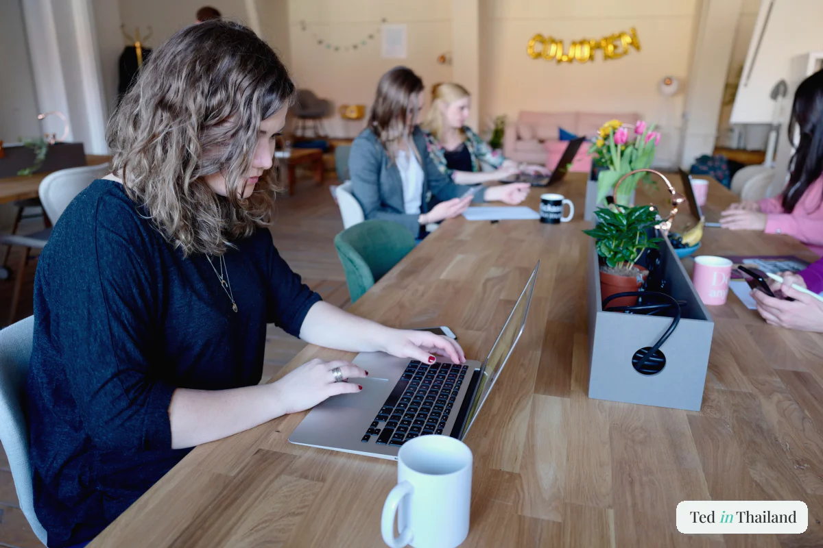 People working on laptops at a shared table in a bright coworking space on Koh Samui with fast WiFi