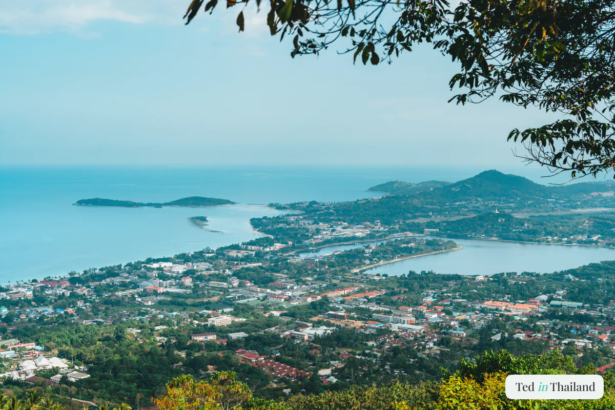 Panoramic Koh Samui viewpoint from a forested hilltop over the coastal town, lagoon and bay