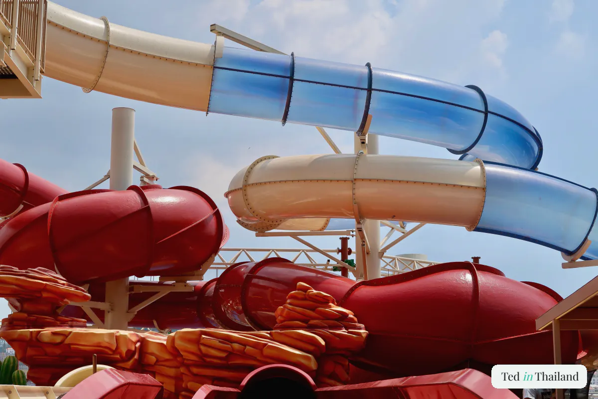 Bright blue and red water slides twisting against a clear sky at a family water park in Koh Samui